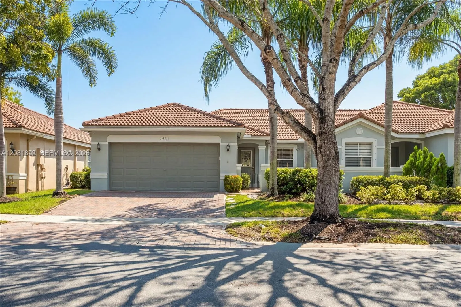 Charming single-story home with tile roof, mature palms, and paver driveway welcomes you home.