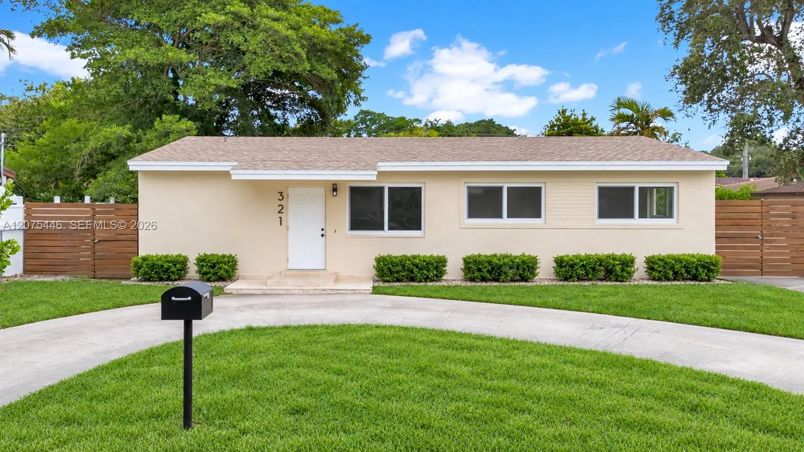 Classic street-facing view of 321 — a well-maintained ranch home with fresh exterior, updated windows, modern wood privacy fencing on both sides, and a generous green front yard. AI-edited photograph for marketing purposes.