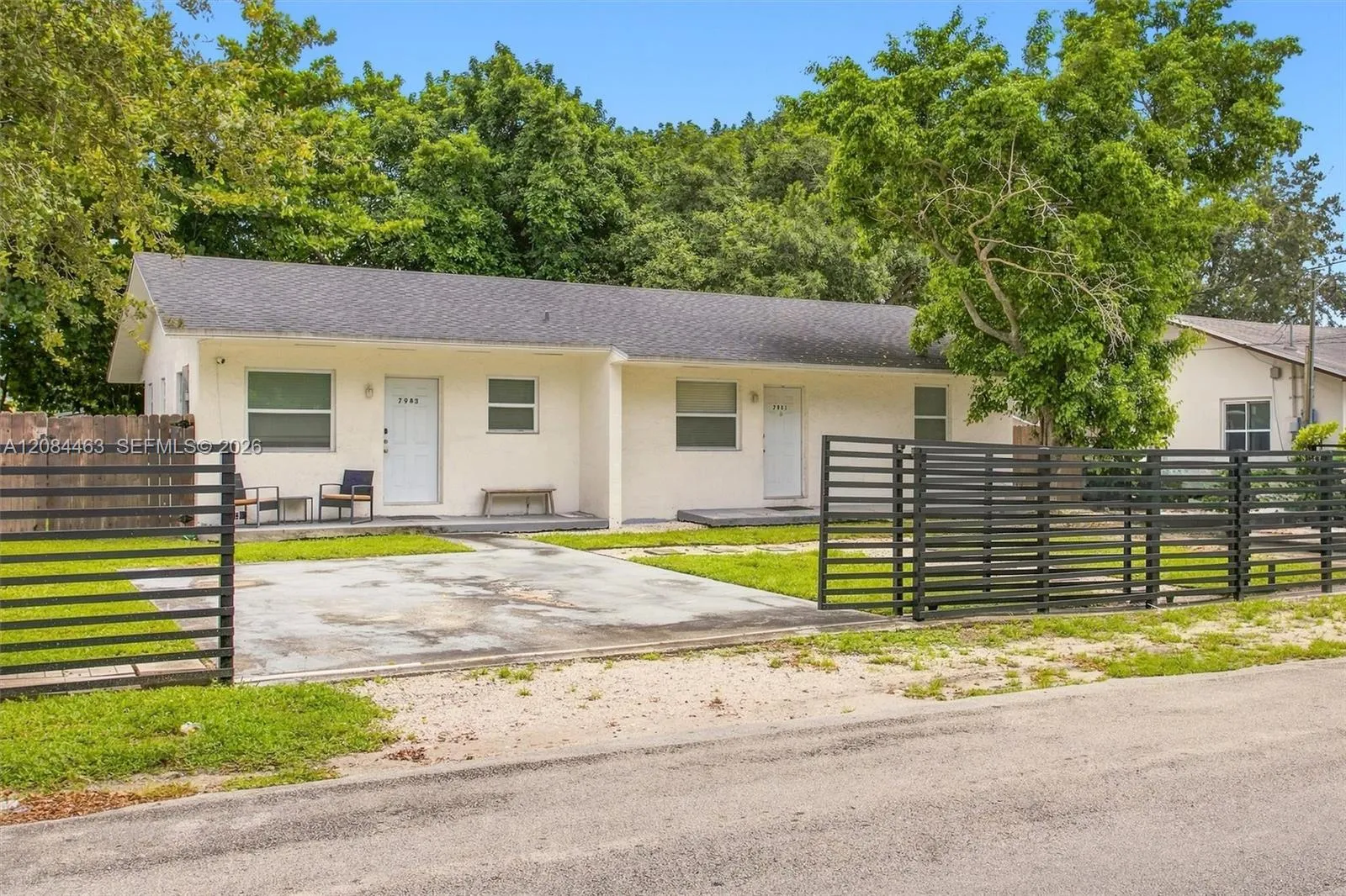 Well-maintained duplex with a clean, inviting exterior, gated parking, and a spacious driveway. Mature trees and surrounding greenery add shade and curb appeal, while the fenced outdoor area provides added privacy and convenience.