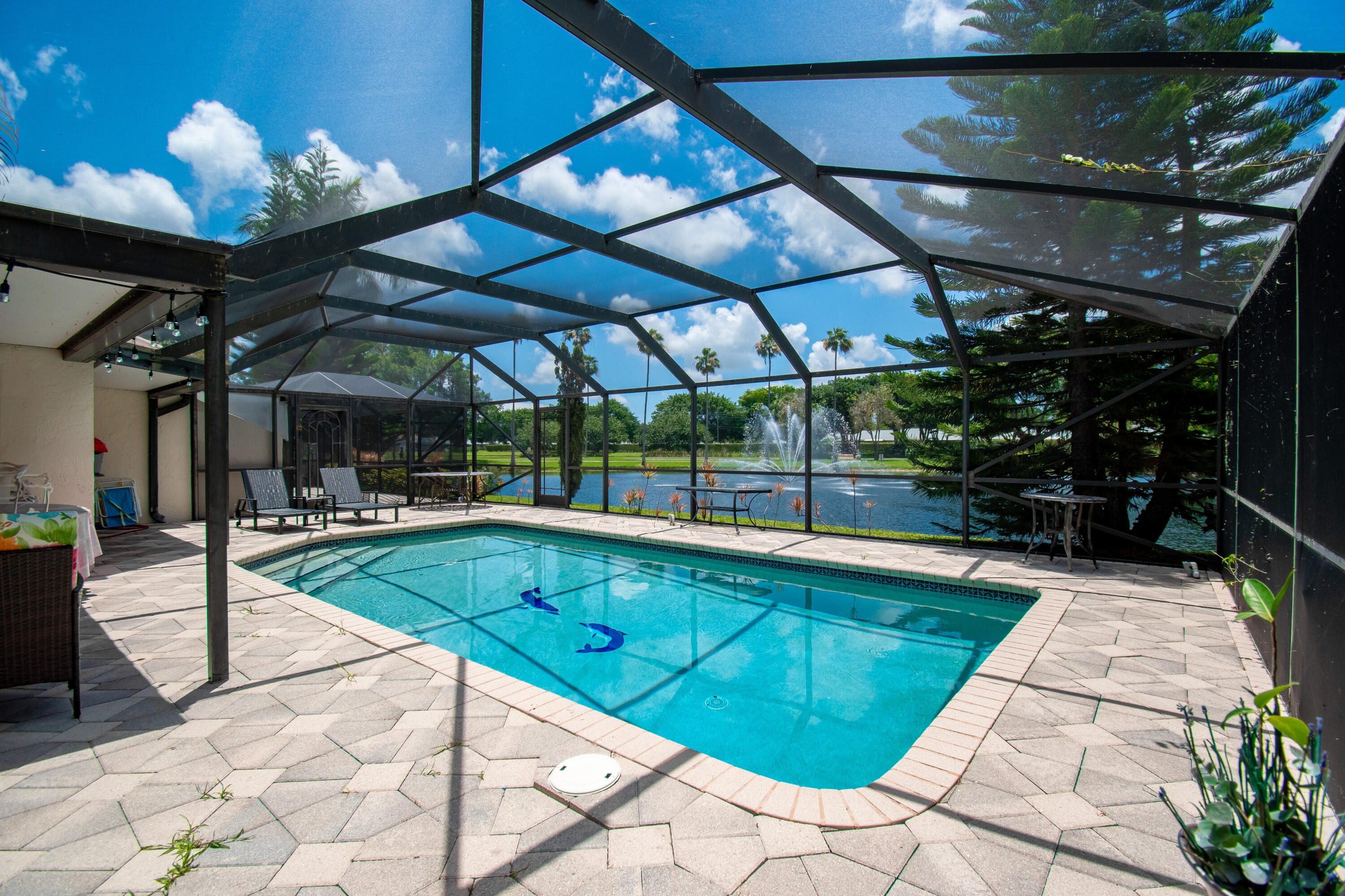 Resort-style screened pool overlooking tranquil lake and fountain views, creating the perfect private outdoor retreat.