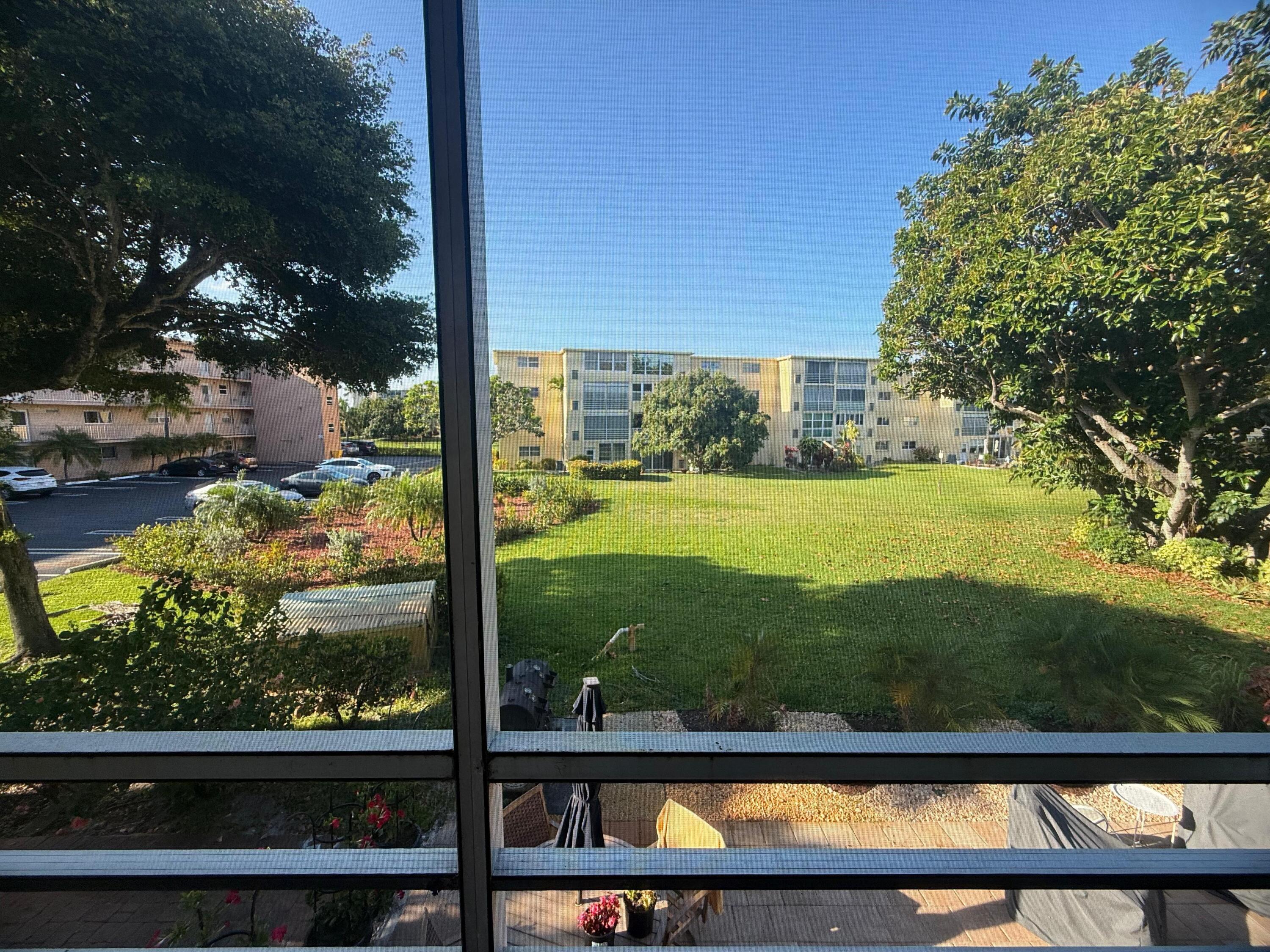 Screened balcony overlooking a landscaped green space with mature trees