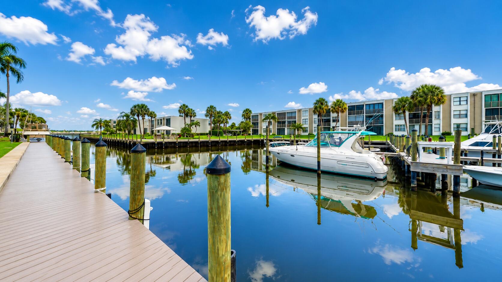 Waterfront property featuring a private boat dock, navigable canal access, direct water frontage, and mature palm landscaping