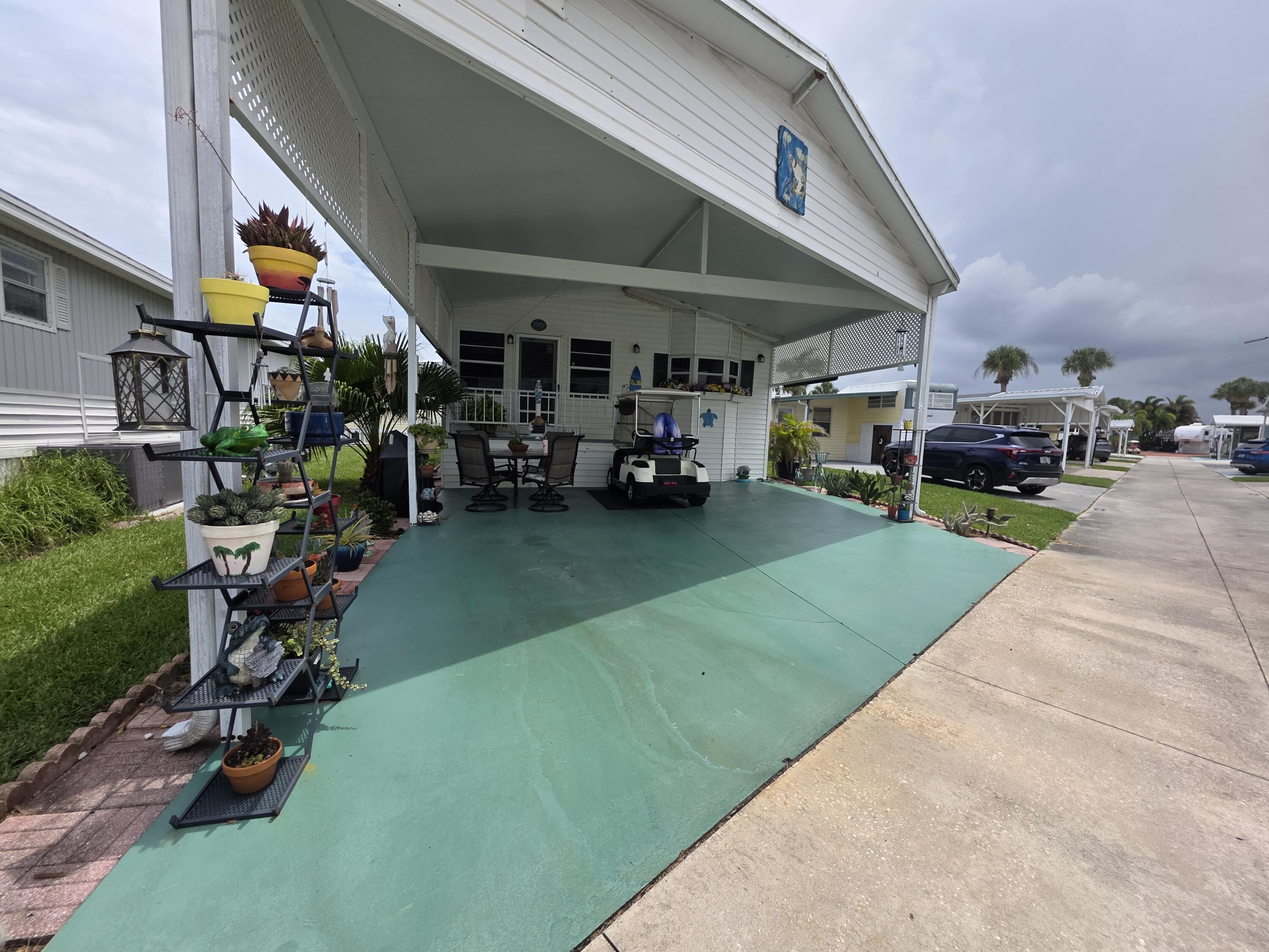 Covered carport with green-painted concrete flooring, offering sheltered outdoor living space