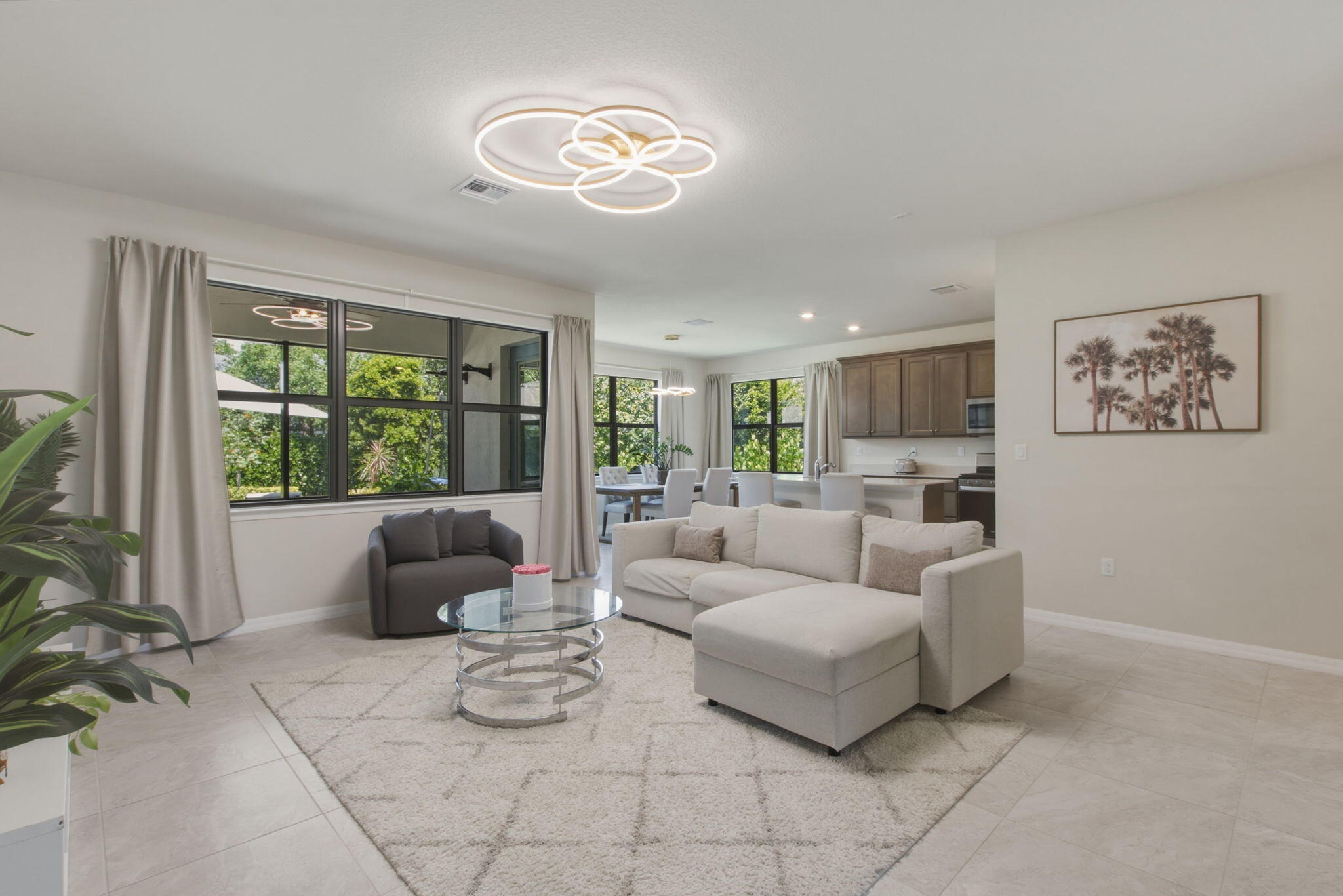 Open-concept living area with large windows, light tile flooring, and recessed lighting