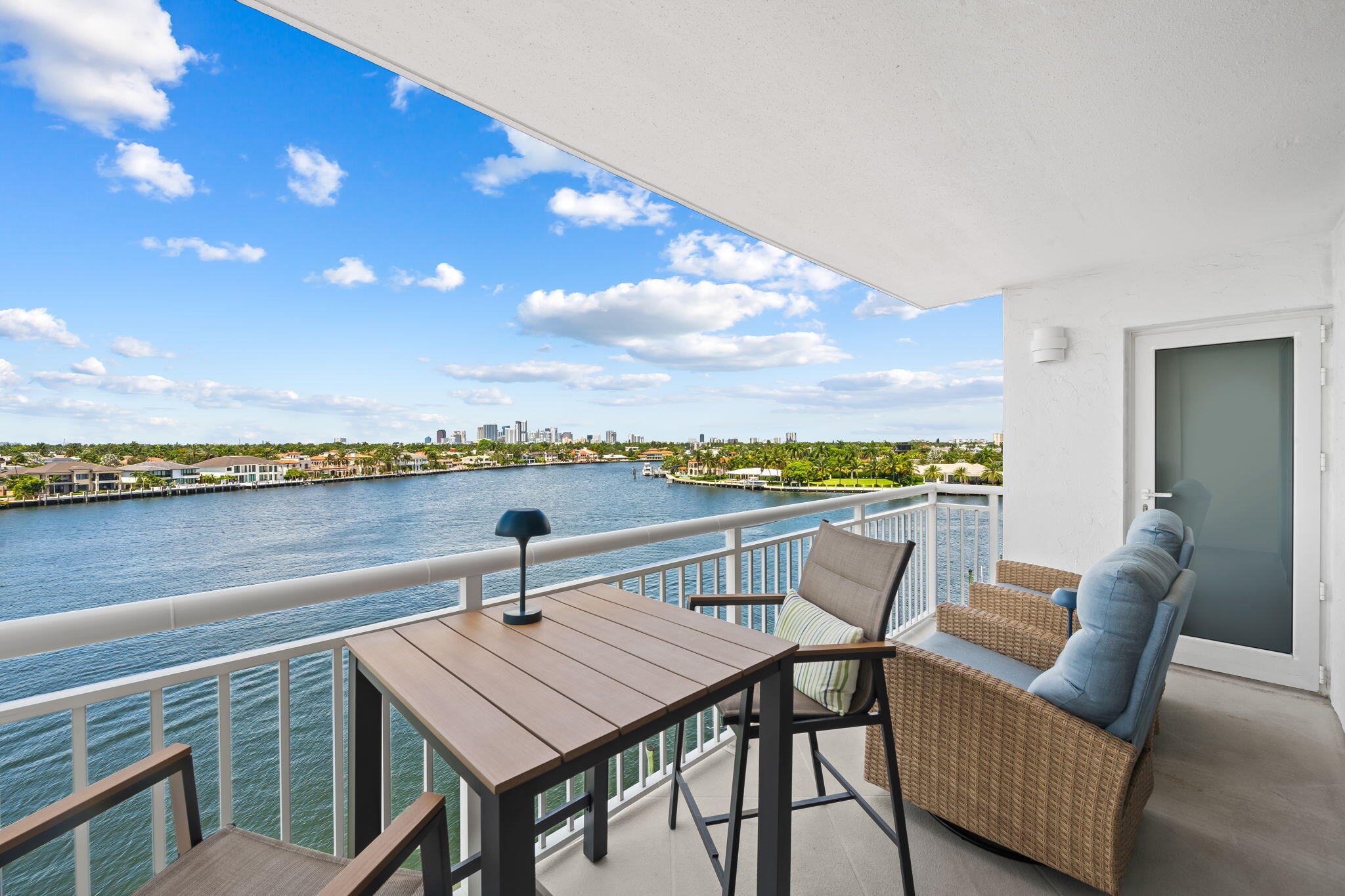 Spacious balcony featuring concrete flooring and white railing overlooking a waterway