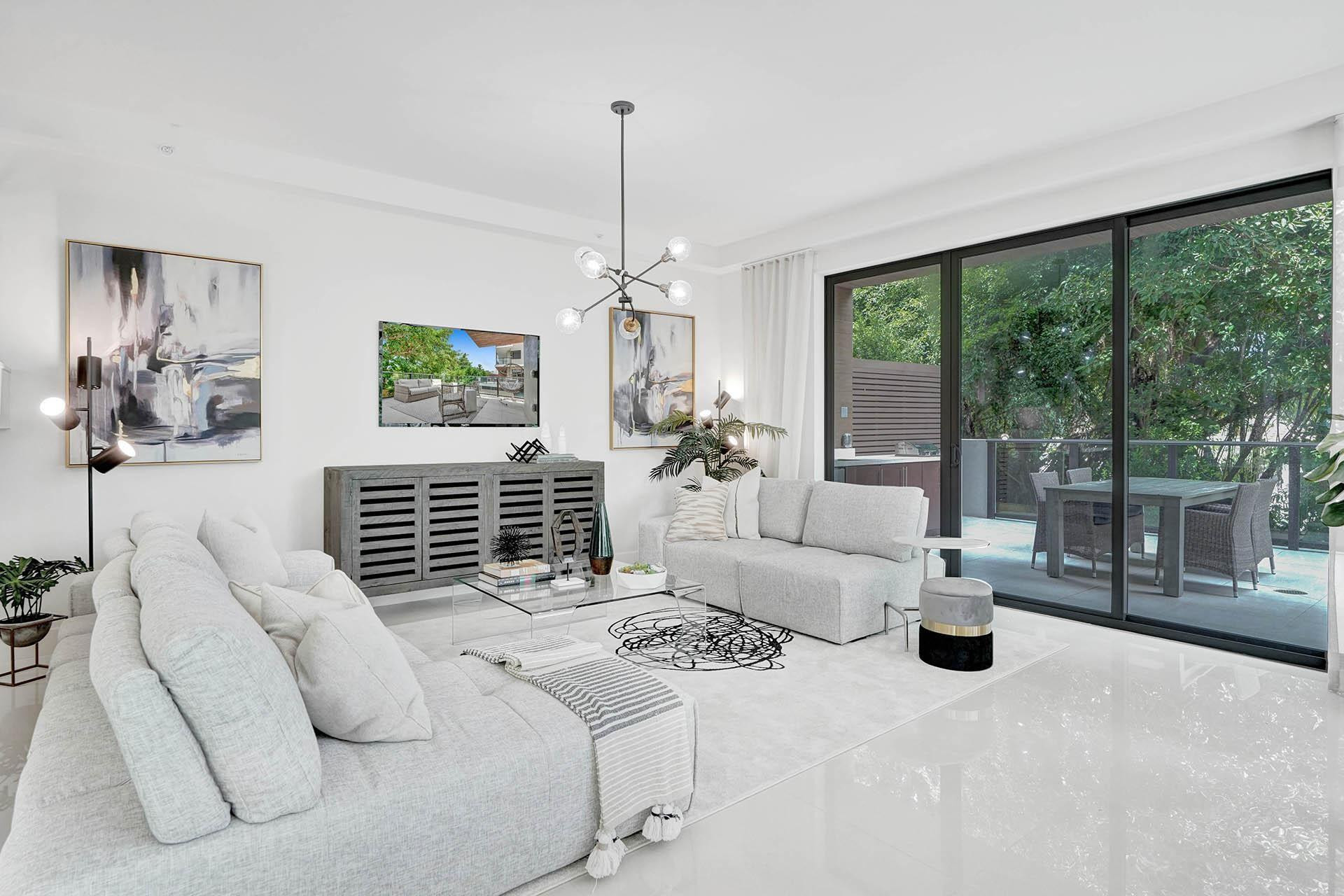 Bright, light-filled living room showcasing floor-to-ceiling glass doors and windows framing lush outdoor greenery