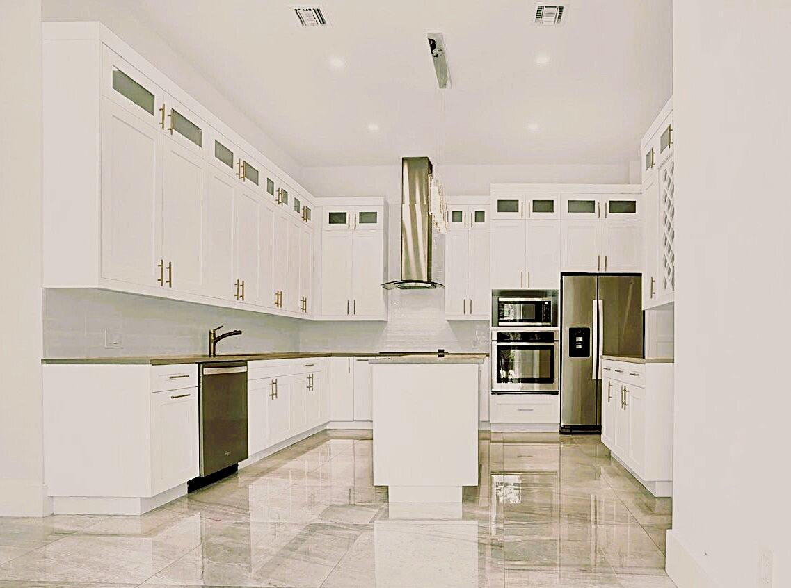 Modern kitchen featuring white cabinetry, stainless steel appliances, a center island, recessed lighting, and large format tile flooring