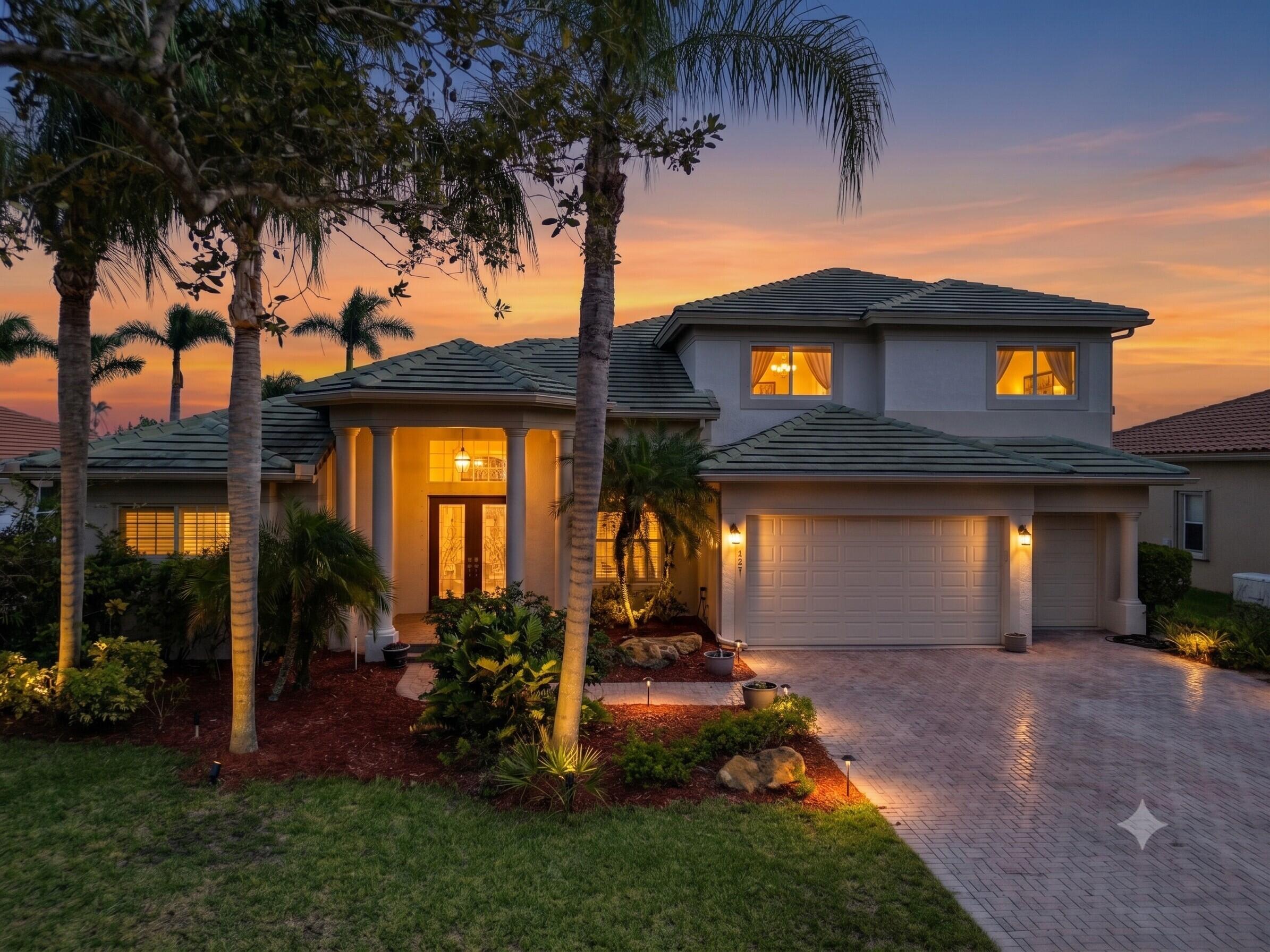 Two-story residence featuring a tile roof, paved driveway, and established landscaping