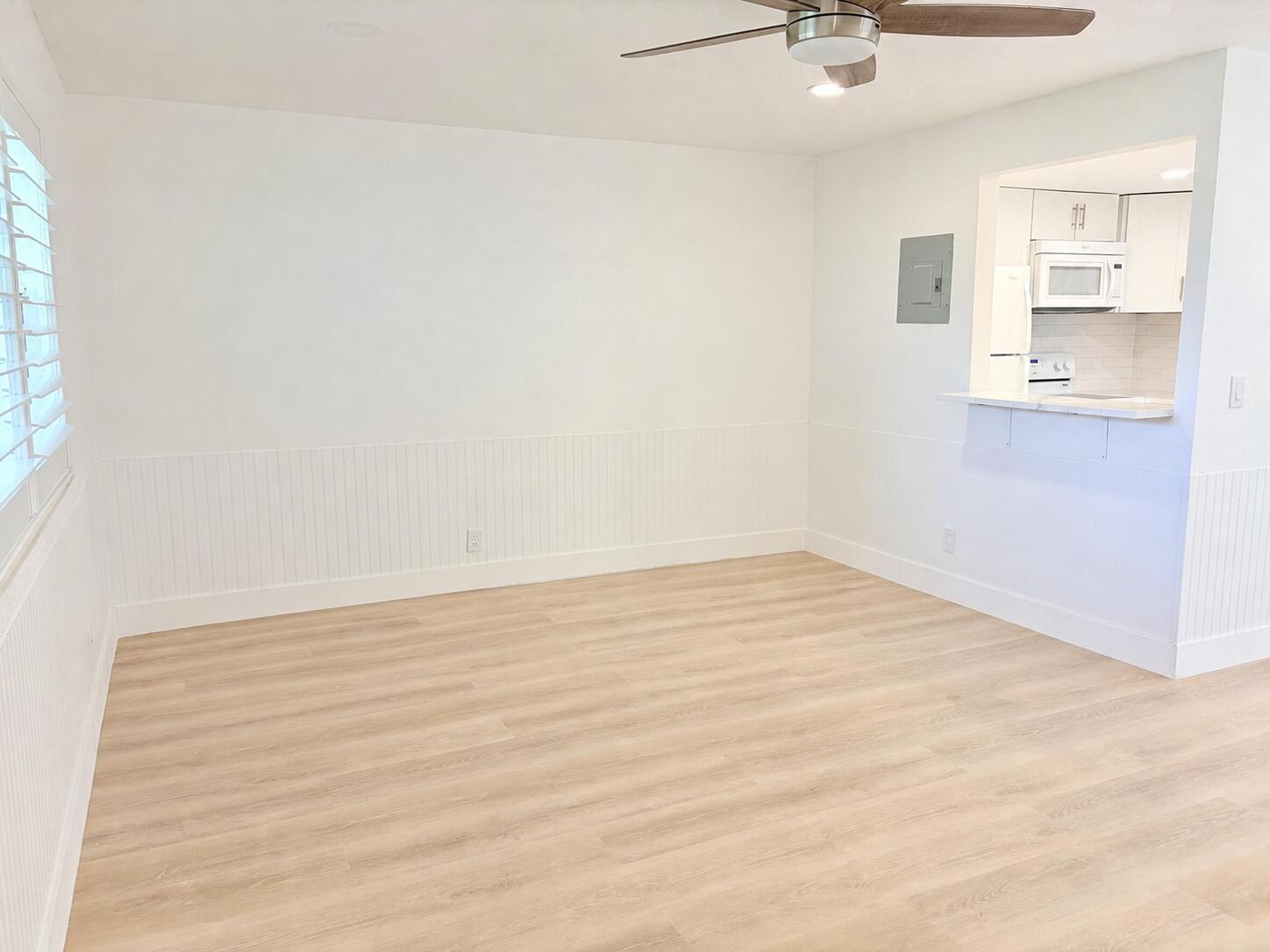 Recessed lighting, ceiling fan with wood-finish blades, wood-finish flooring, wainscoting, and a pass-through kitchen opening