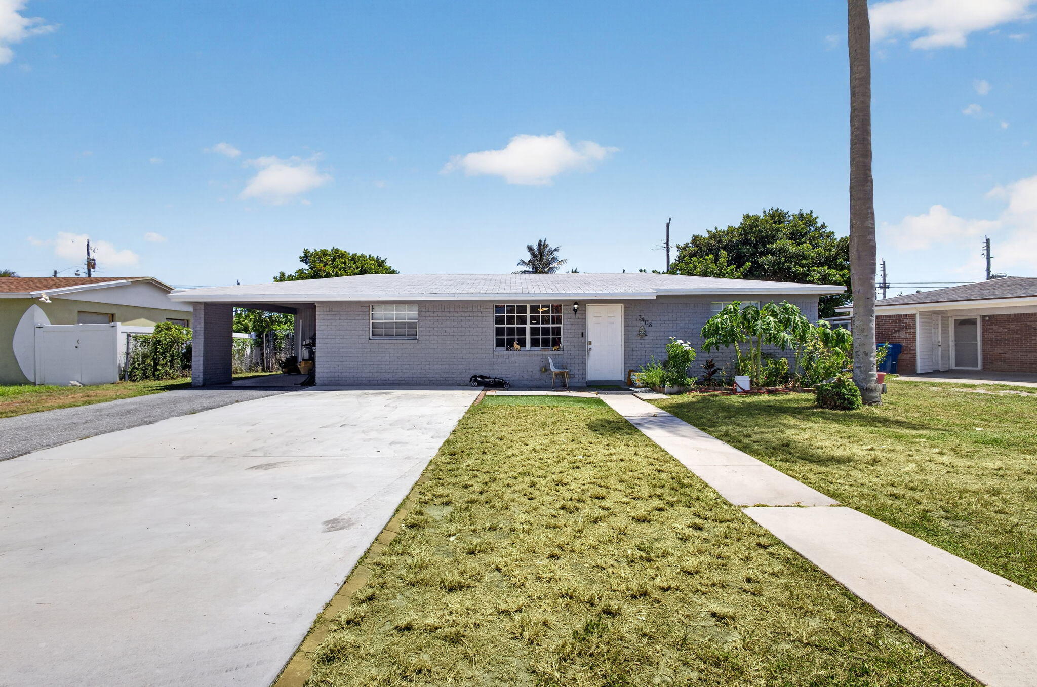 Light gray exterior with white trim, a covered carport, and a concrete driveway