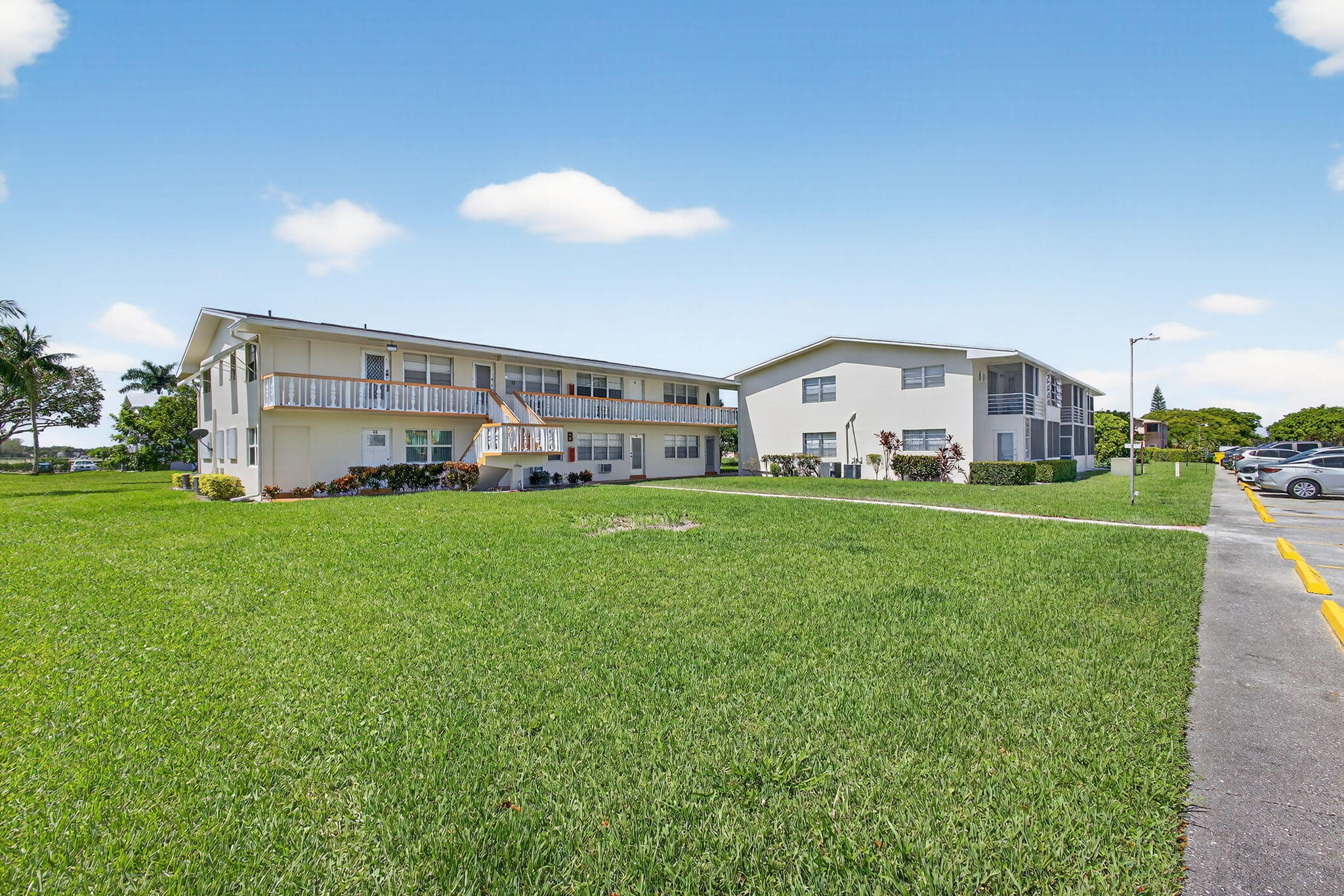 Expansive lawn areas, multi-story buildings with balconies, dedicated parking facilities, and lush landscaping
