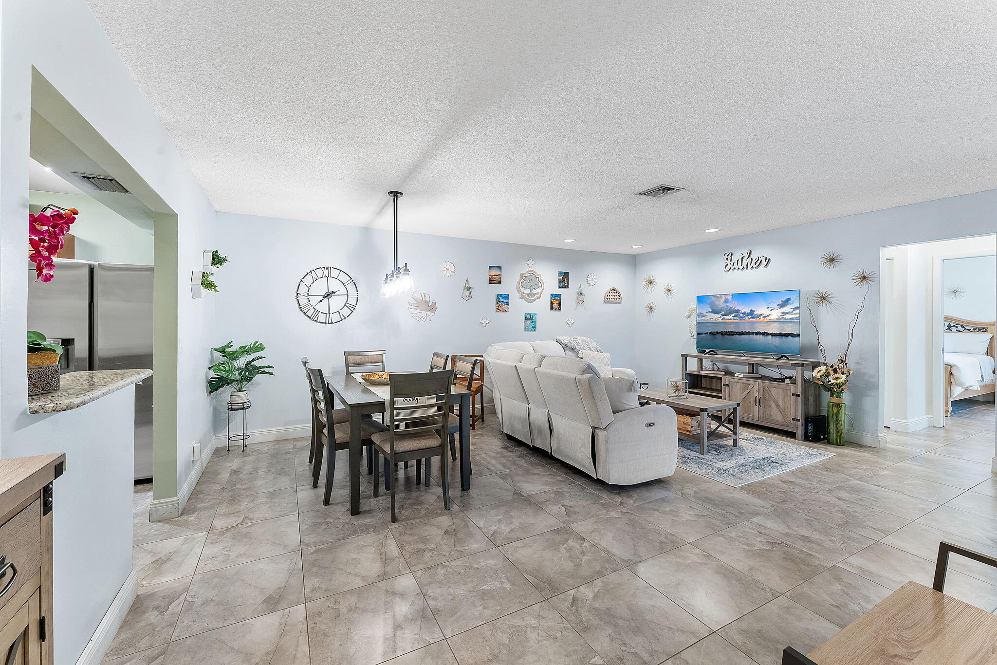 Open-concept living area showcasing polished stone-finish flooring, recessed lighting, and abundant natural light from multiple windows