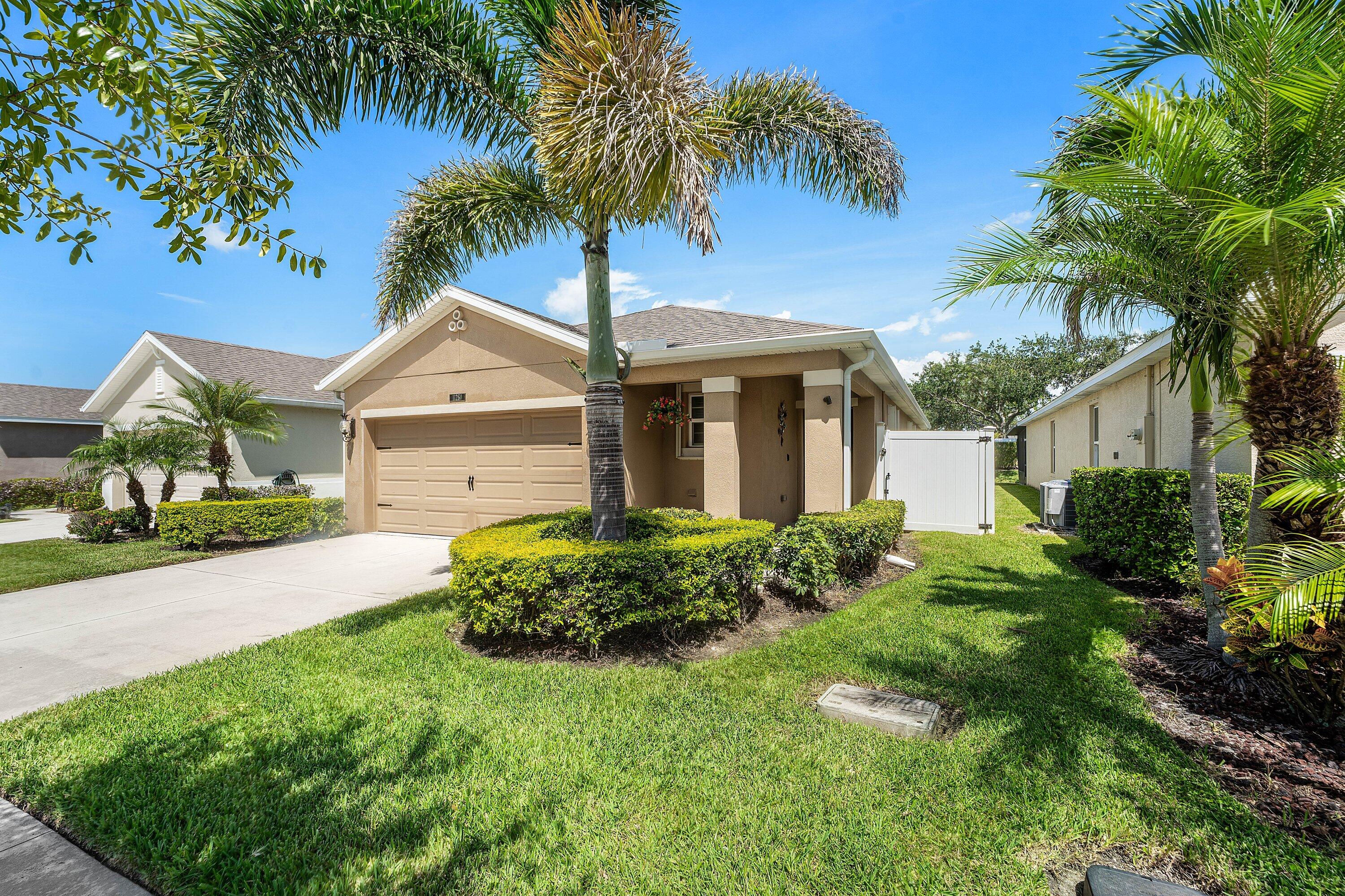 Single-story residence featuring a two-car garage, concrete driveway, and established landscaping