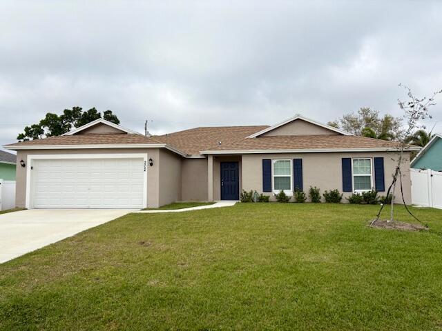 Single-story residence featuring a brown shingle roof, beige exterior stucco, and a dark blue front door