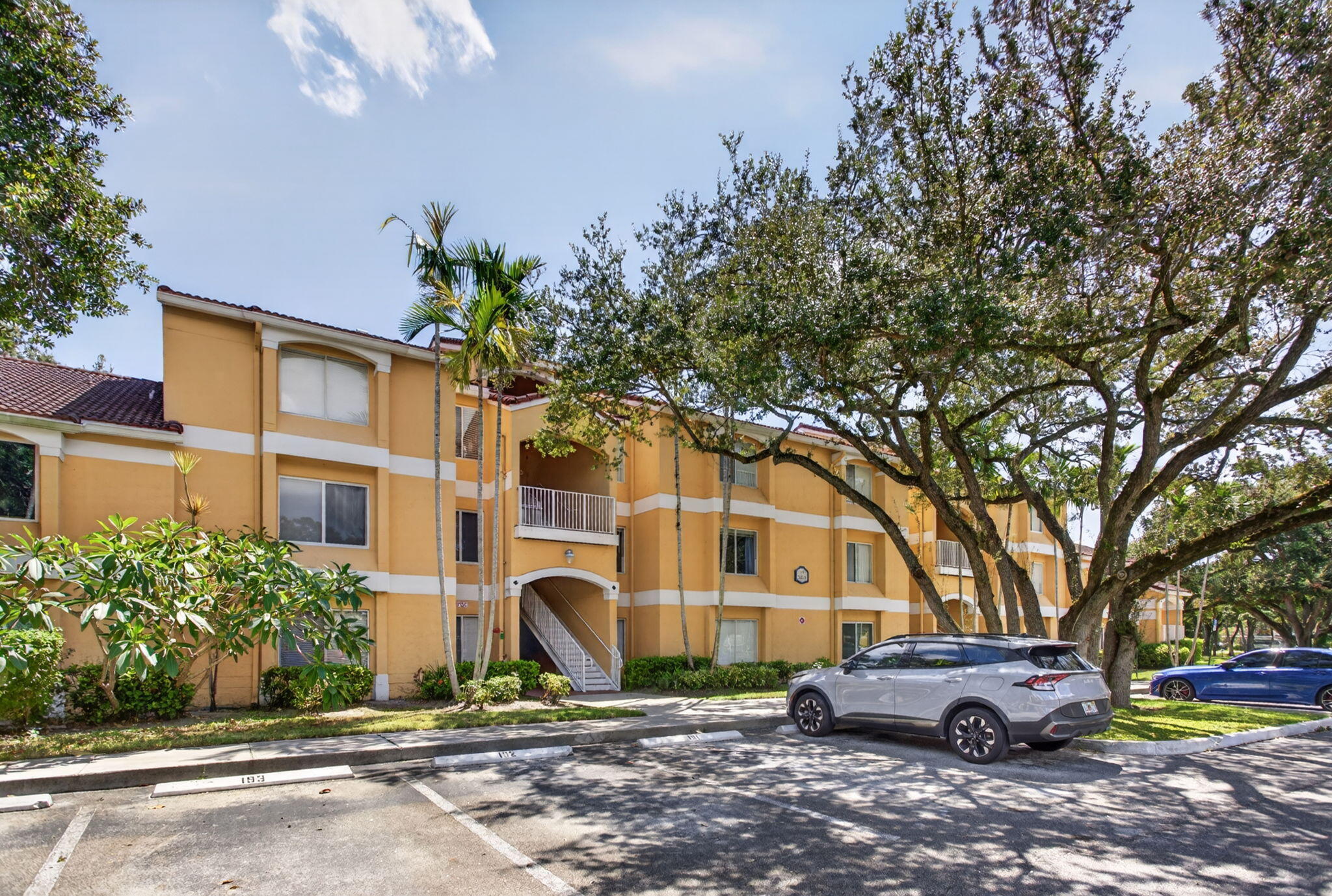 Three-story building with a terracotta tile roof and light yellow stucco exterior