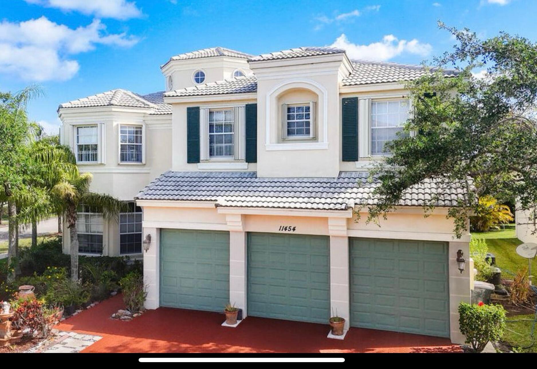 Elegant two-story residence featuring a cream-colored stucco exterior with dark green shutters, tile roof, and architectural detailing