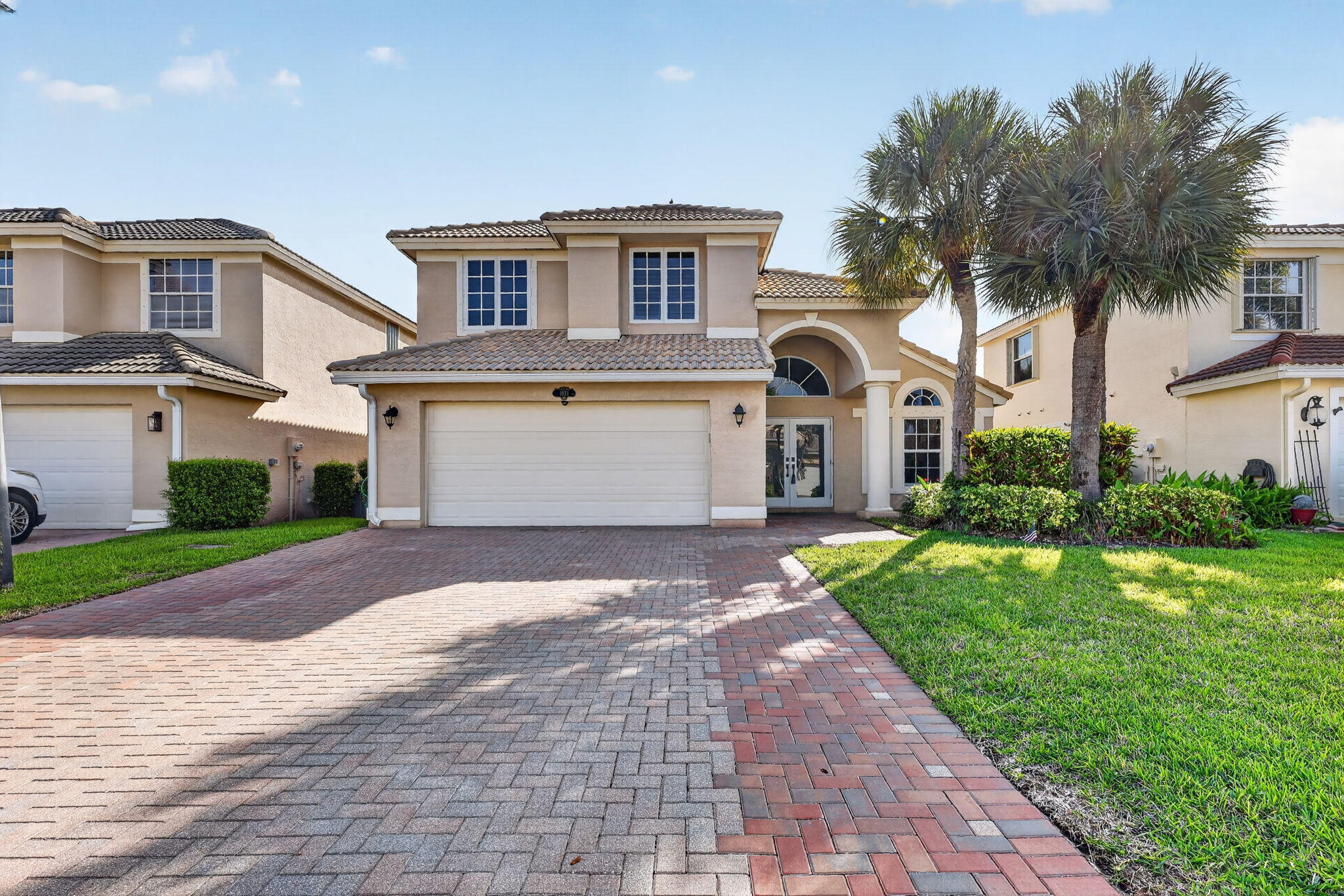 Two-story stucco exterior with a tiled roof, arched entryway, and an integrated two-car garage