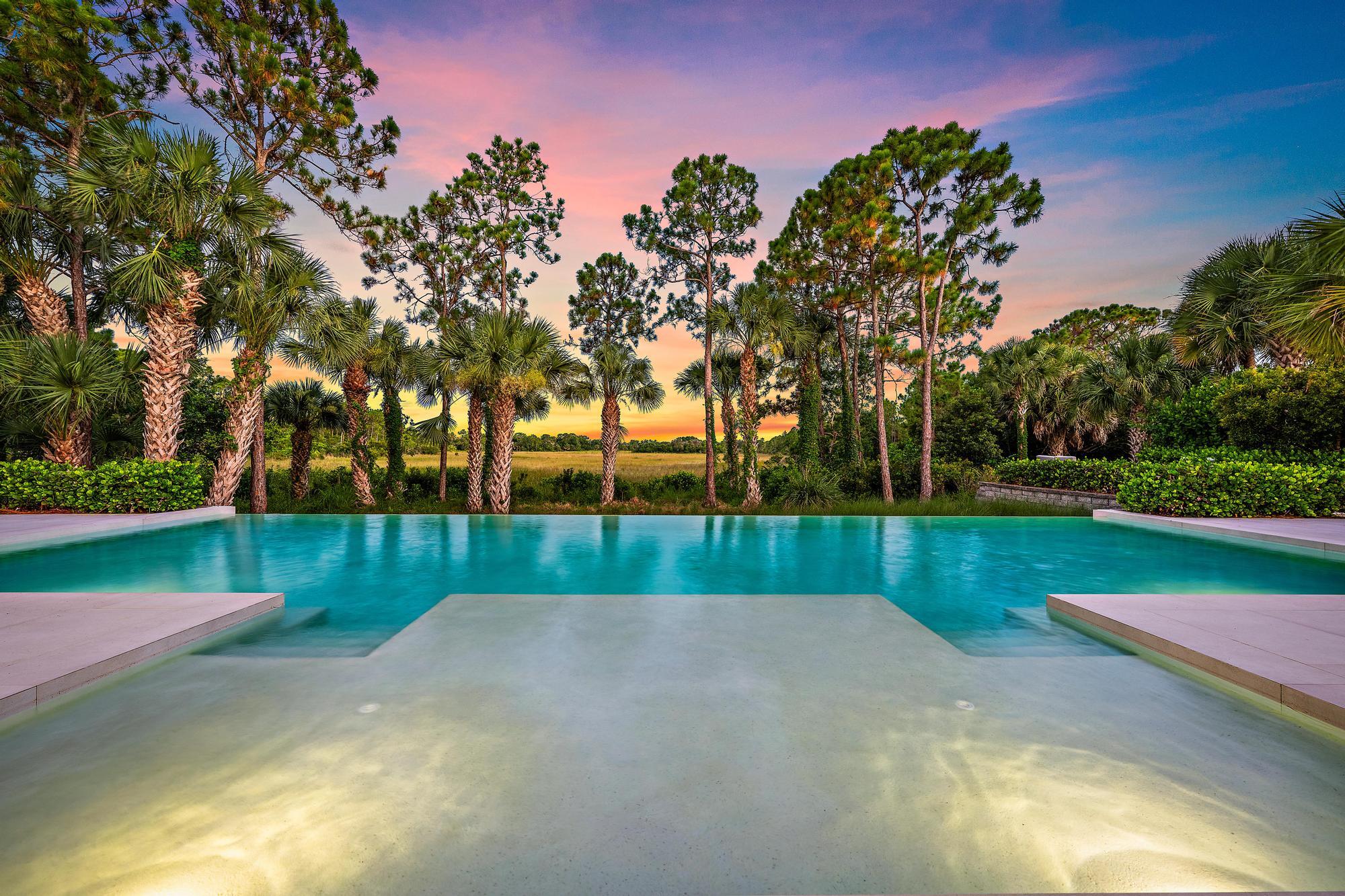 Infinity-edge pool with integrated steps, surrounded by lush tropical landscaping and mature trees