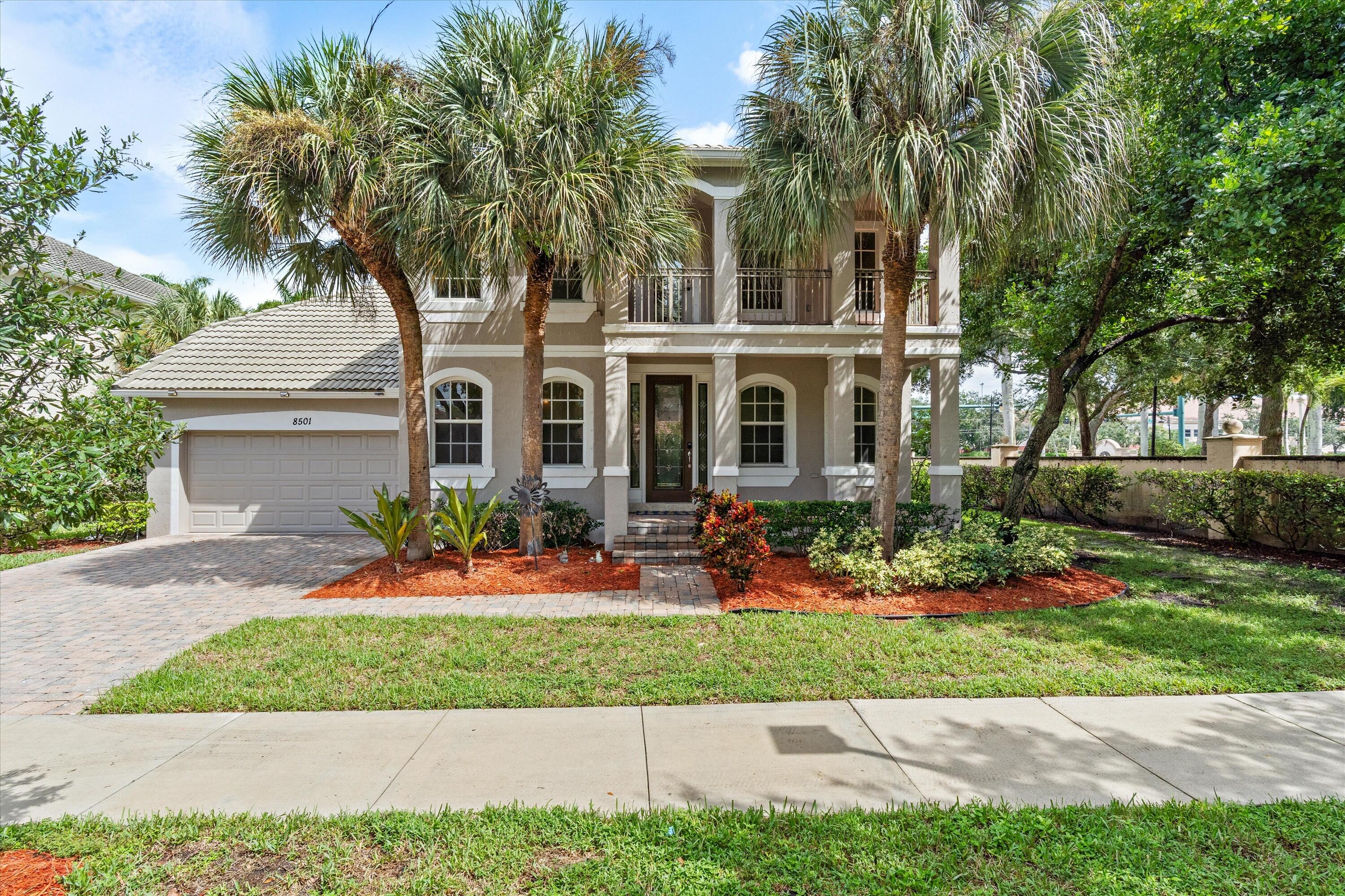 Two-story residence featuring a tile roof, an integrated two-car garage, and a paver driveway