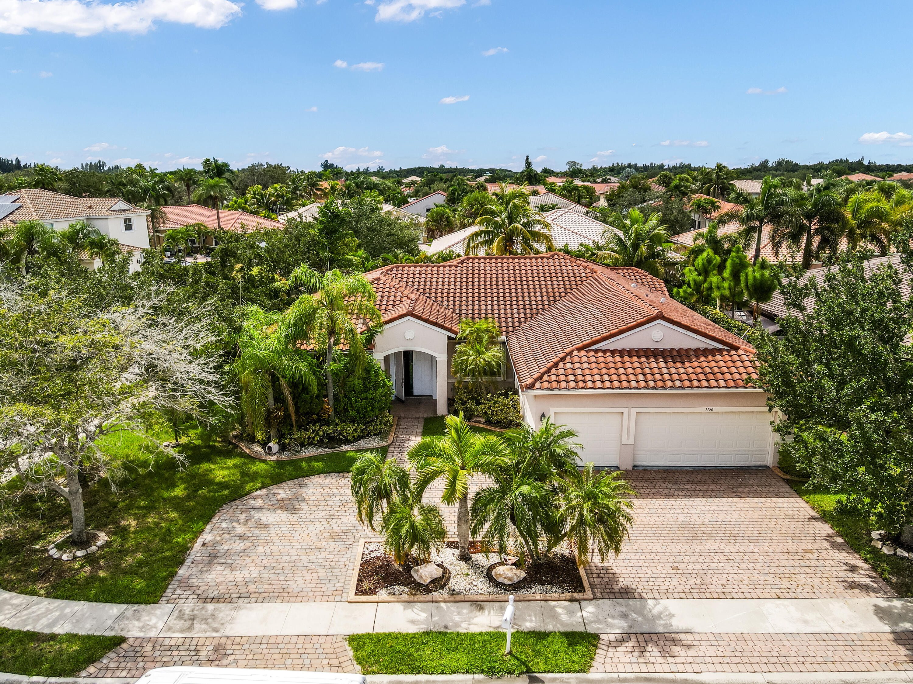 Tile roof, Three-car garage, mature landscaping, paved driveway, and covered entry
