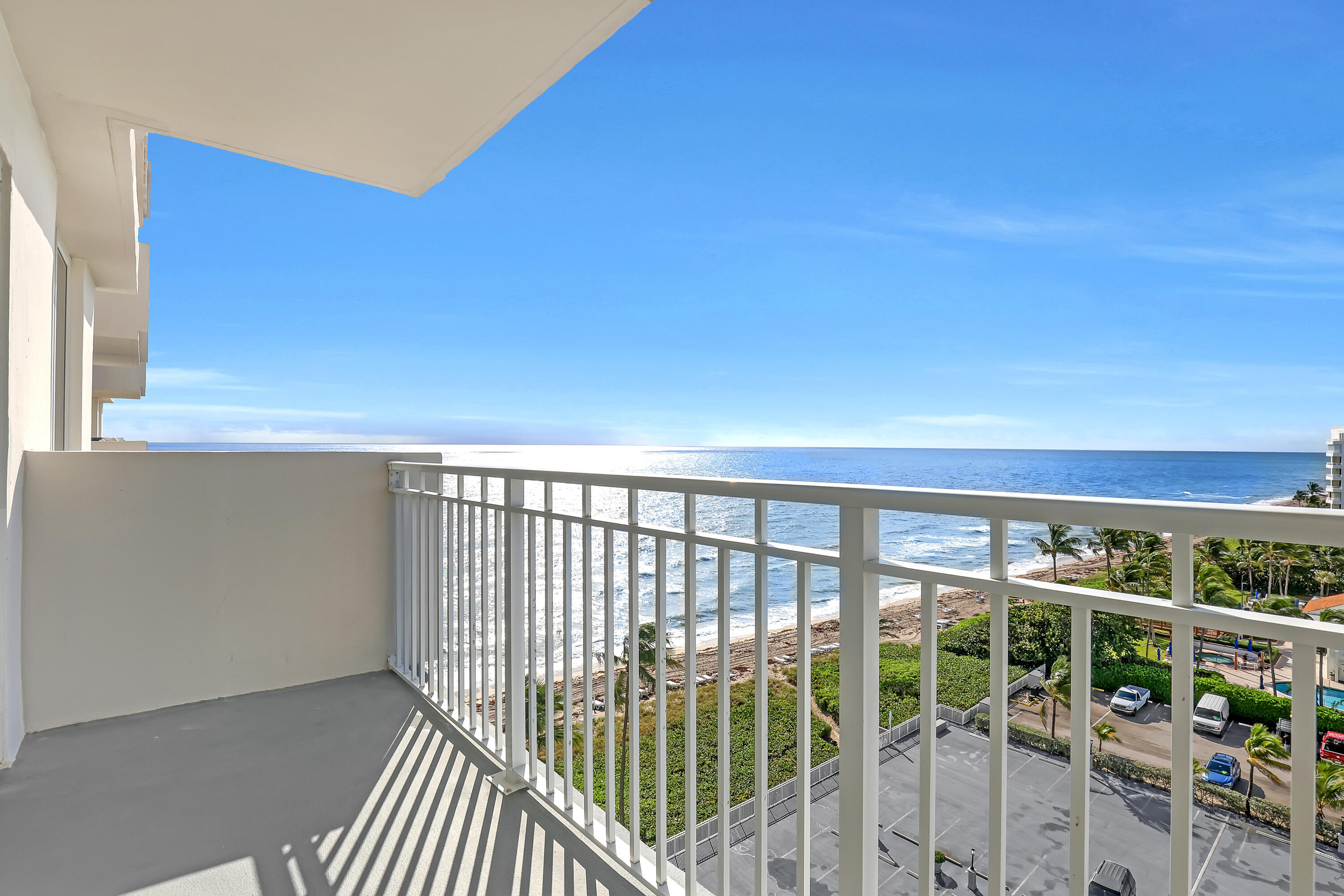 Private balcony with white metal railing, offering expansive ocean and coastline scenery