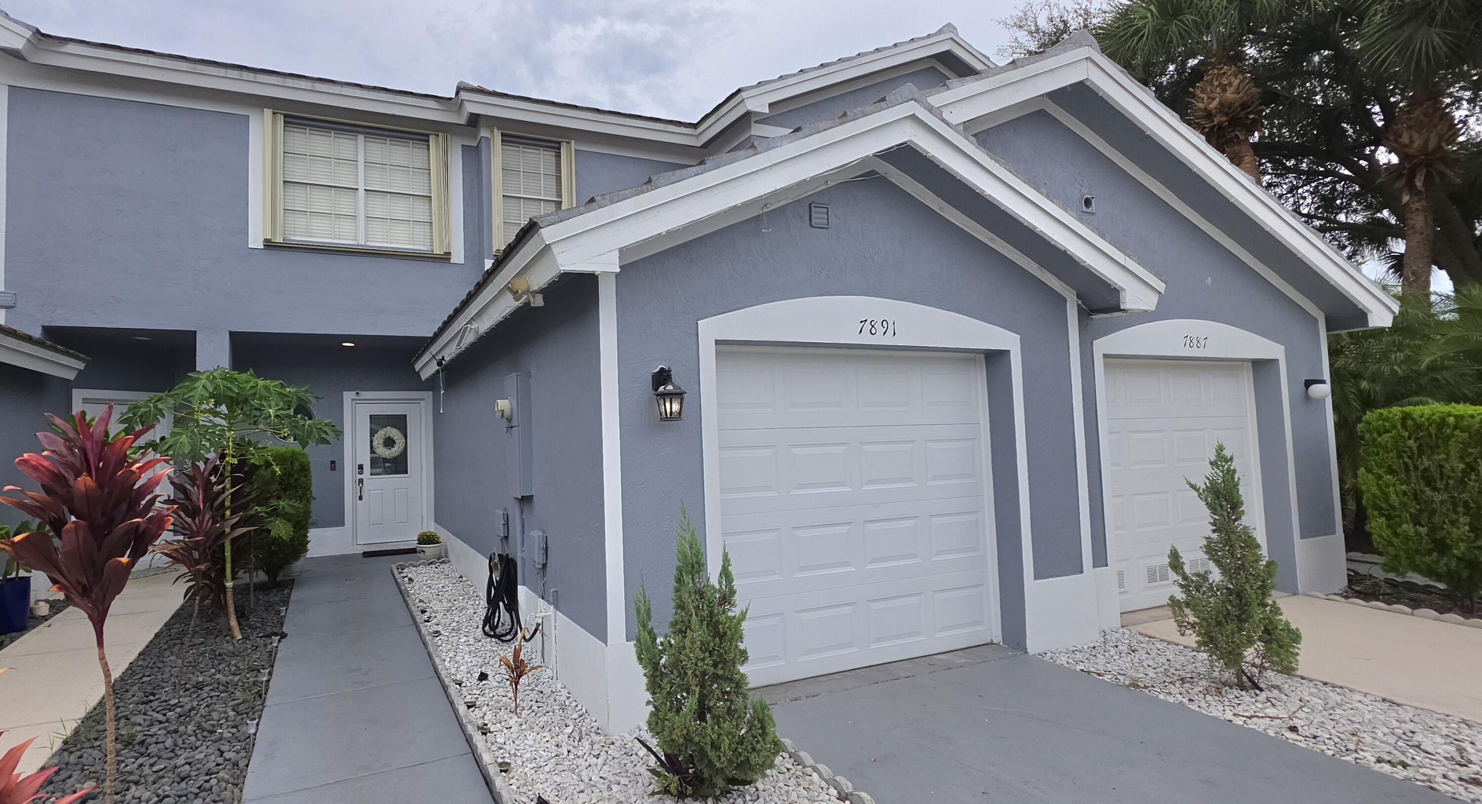 Stucco exterior with white trim, two white paneled garage doors, and a white front entry door with a frosted glass insert