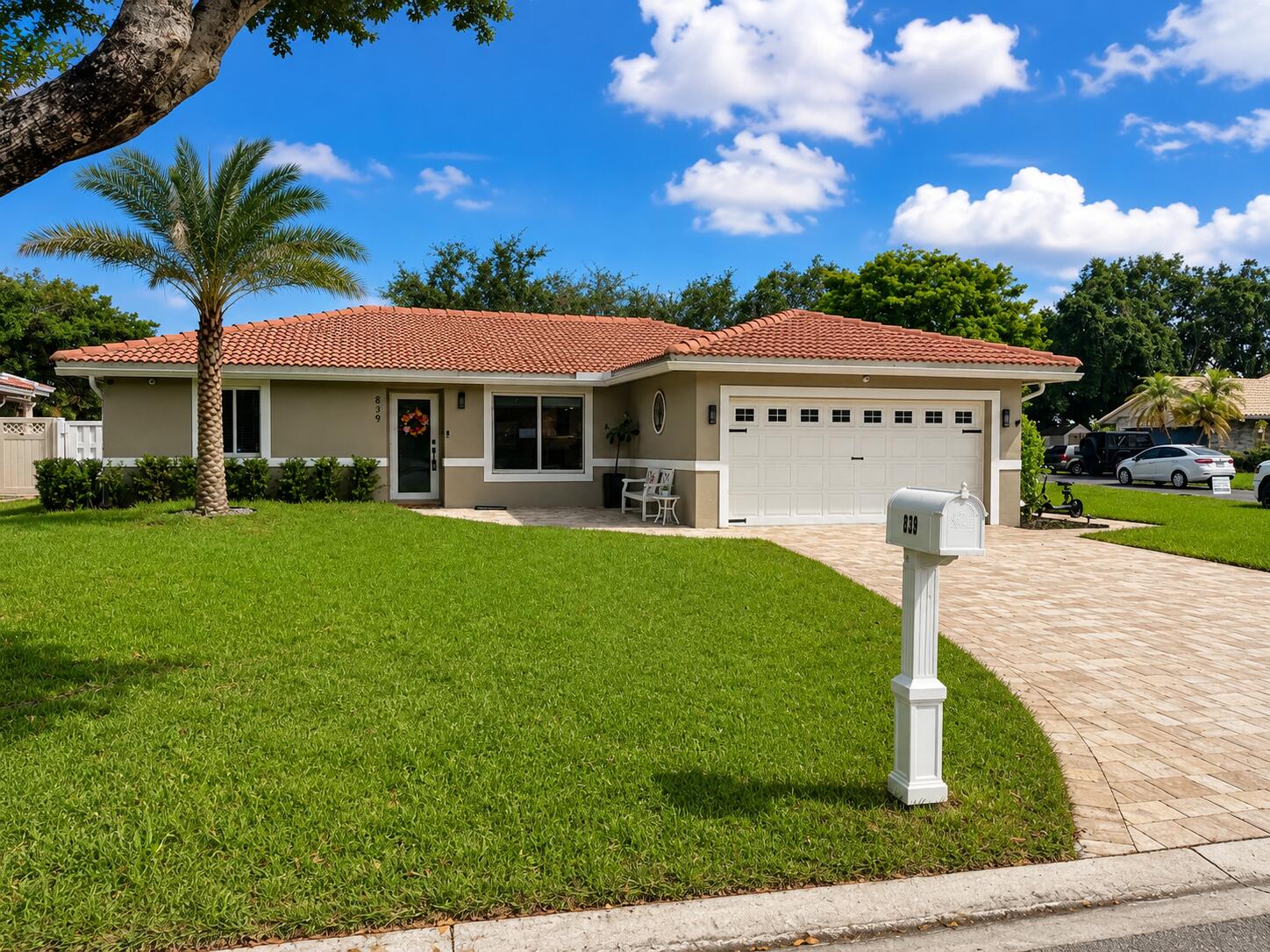Mediterranean-style roof tiles, stucco exterior, attached garage, paver driveway, and mature landscaping