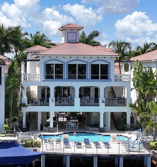 Mediterranean-style architecture with tile roofing, a central swimming pool with surrounding deck, multiple covered balconies, and a private dock with boat slips