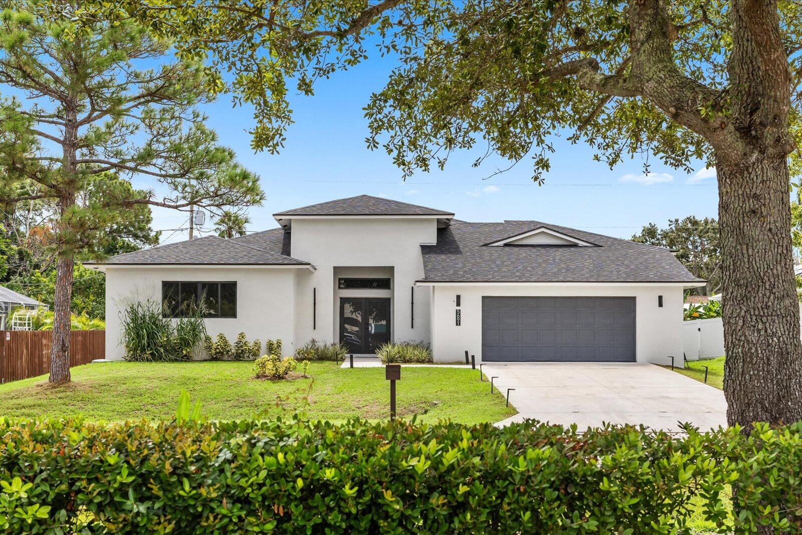 Contemporary exterior with a white stucco finish, dark shingle roof, and an integrated two-car garage