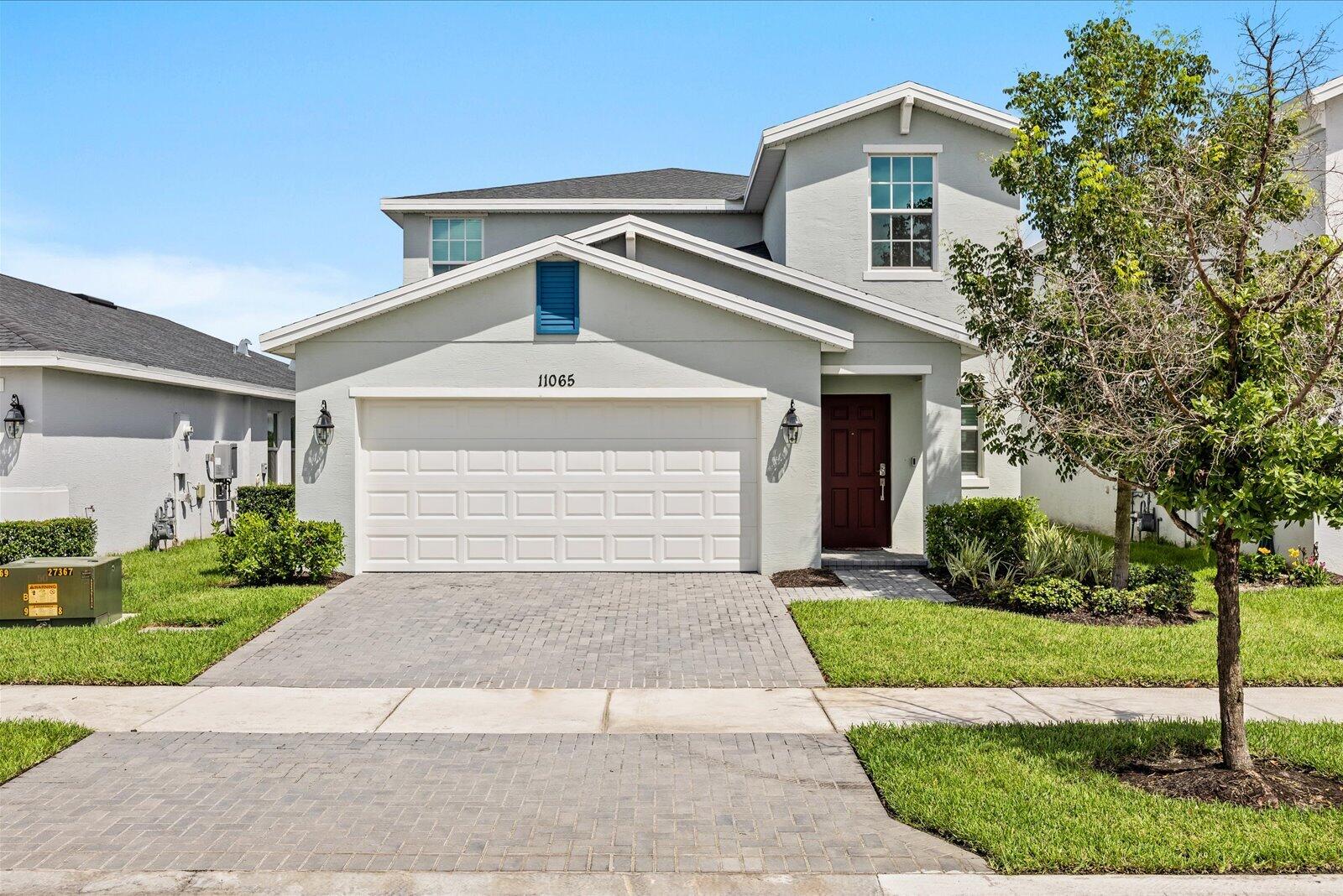 Two-story residence featuring a two-car garage, paver driveway, and a welcoming front entry