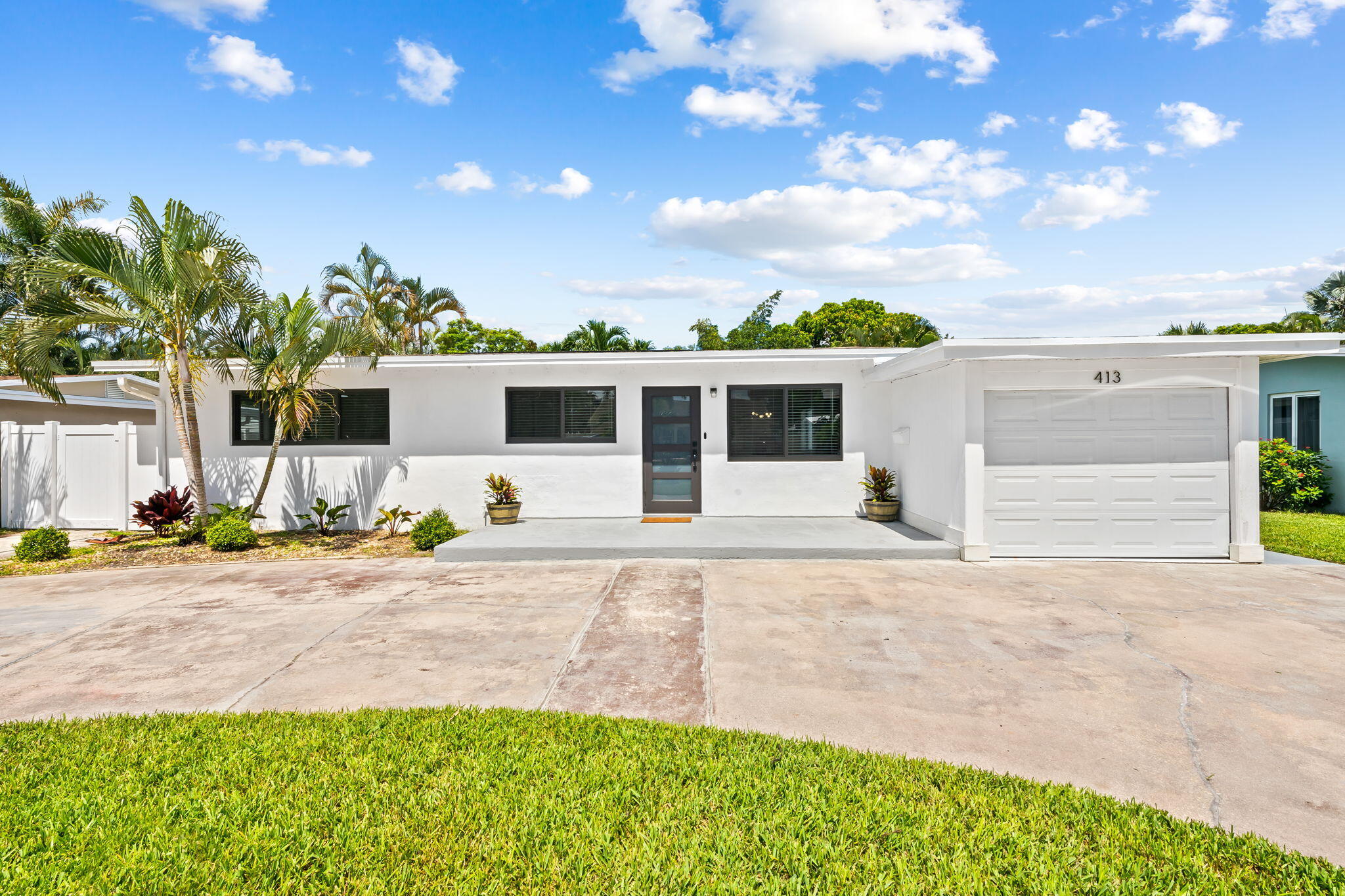 Contemporary white exterior, dark-framed windows, and an attached garage with a panel door
