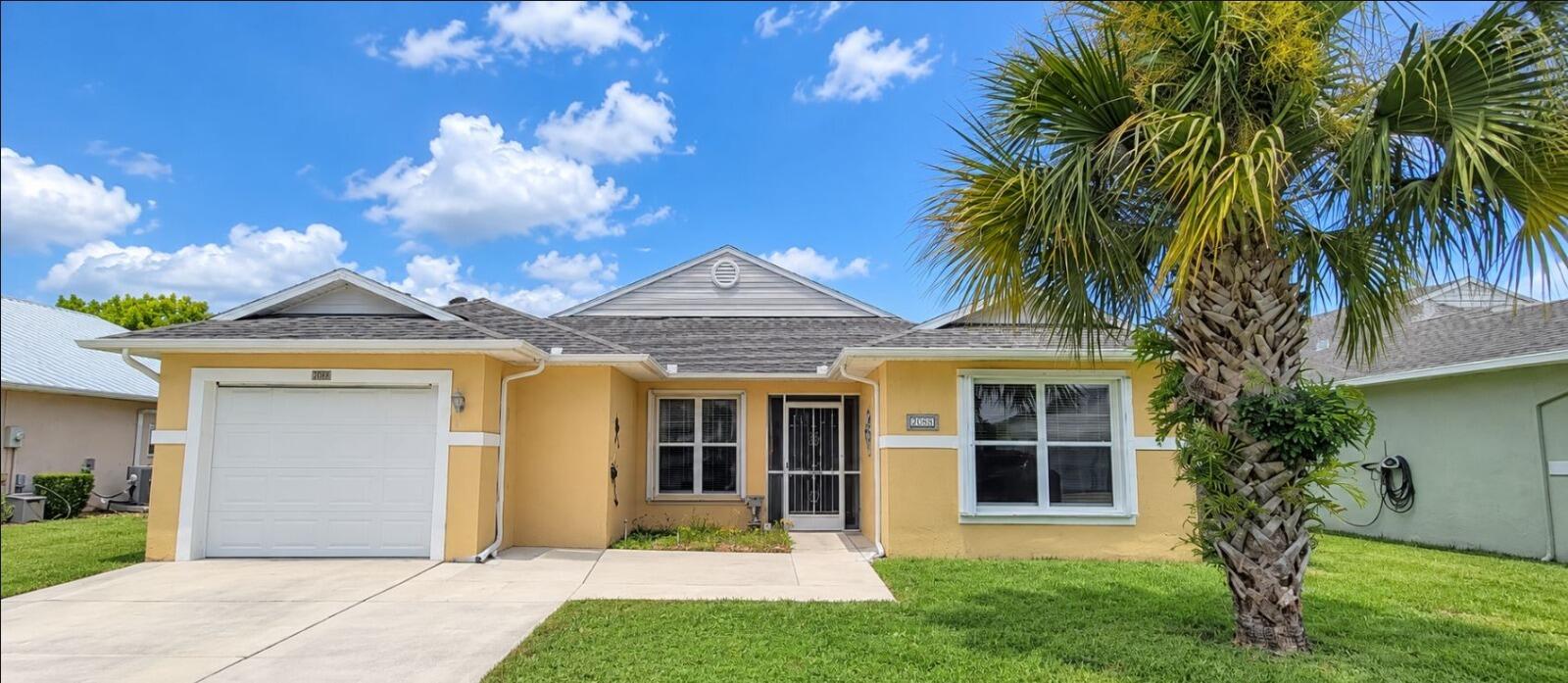 Front view of the home featuring an attached garage, driveway, and landscaped yard.