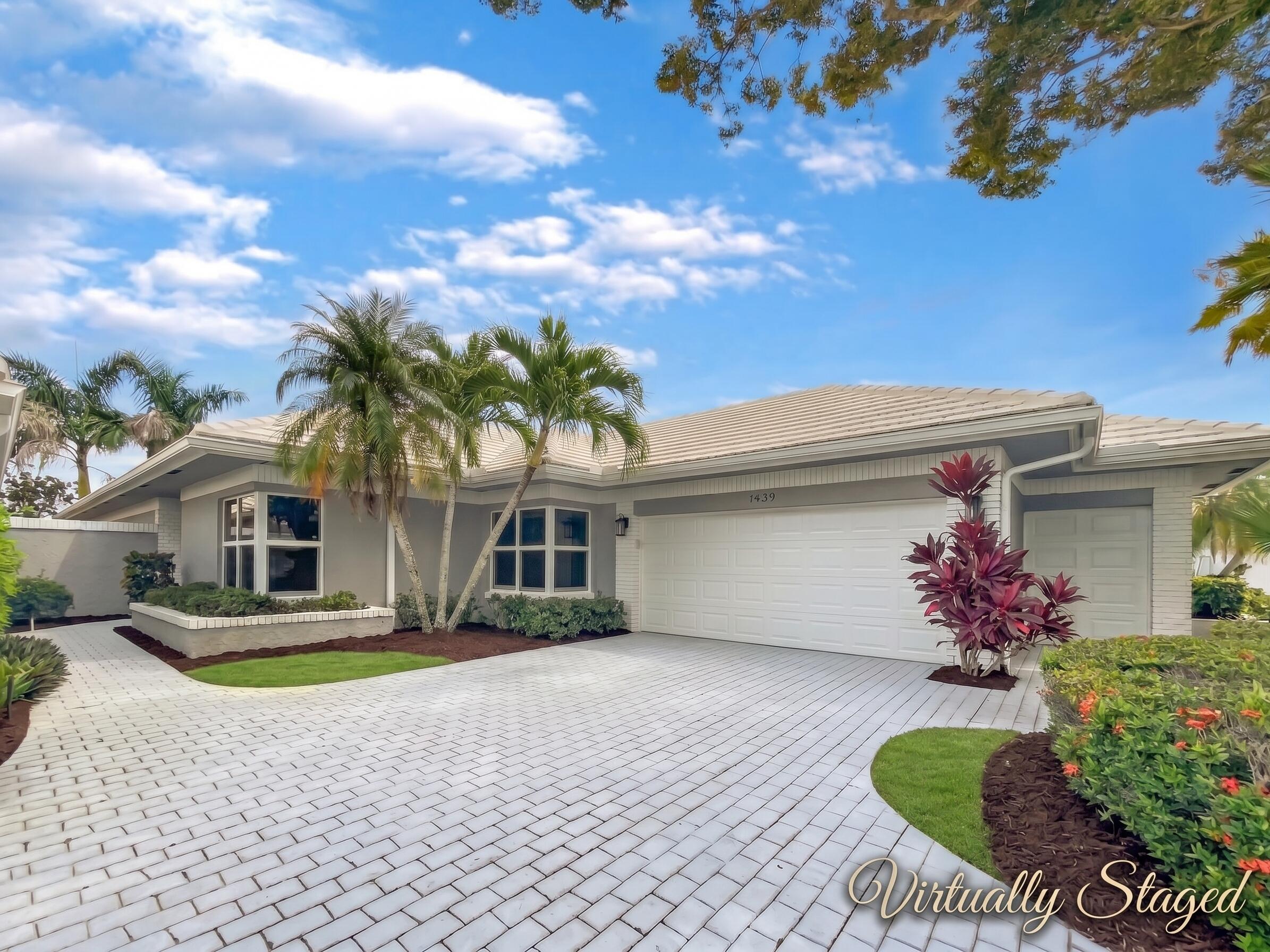 Paved driveway, attached two-car plus golf cart garage, mature palm trees, bay windows, and well-maintained landscaping
