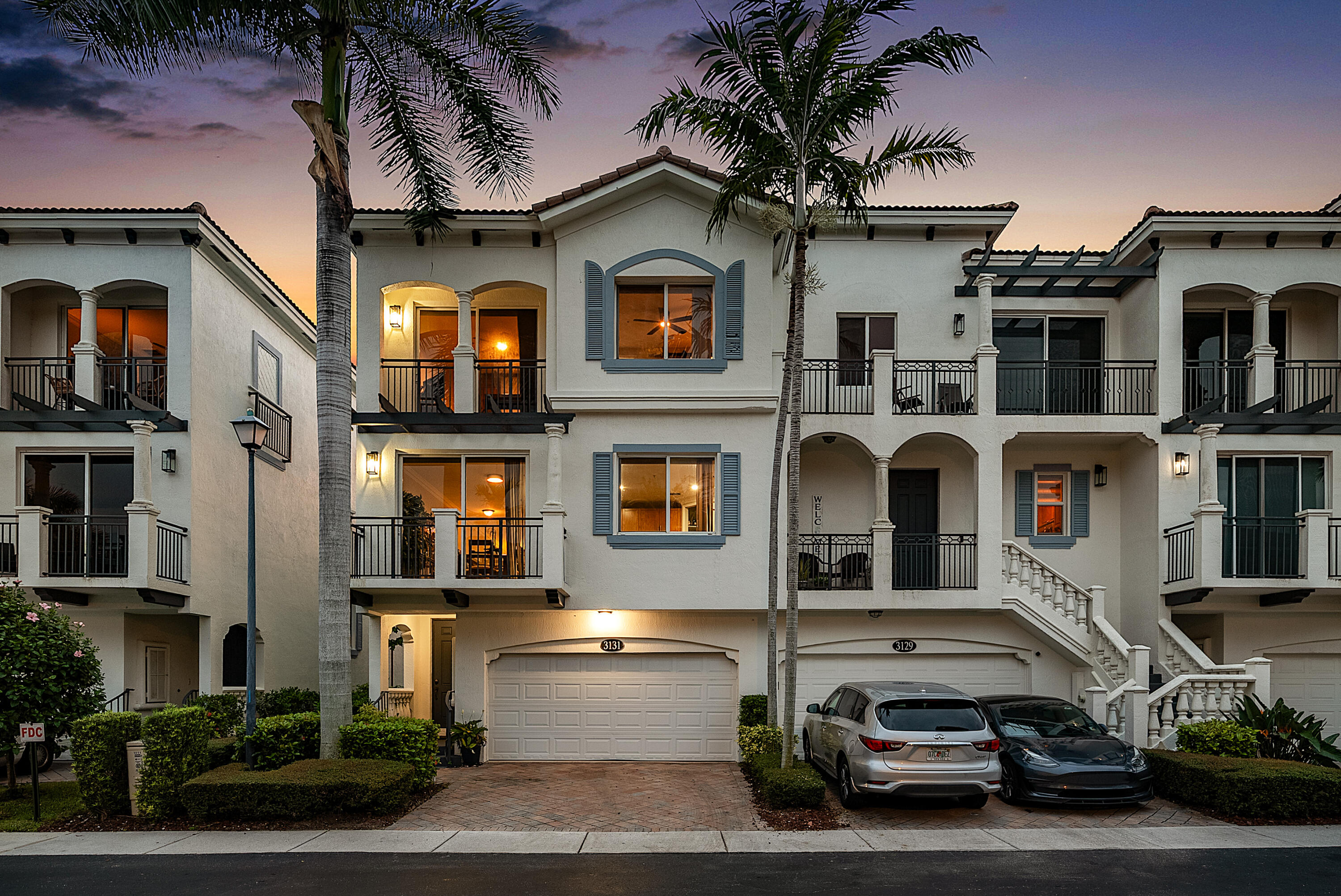 Coastal-mediterranean-inspired exterior with multi-level balconies, decorative shutters, and attached 2-car garage