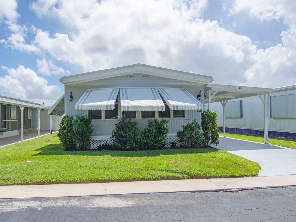 Manufactured home with an attached carport, exterior awnings, and manicured landscaping