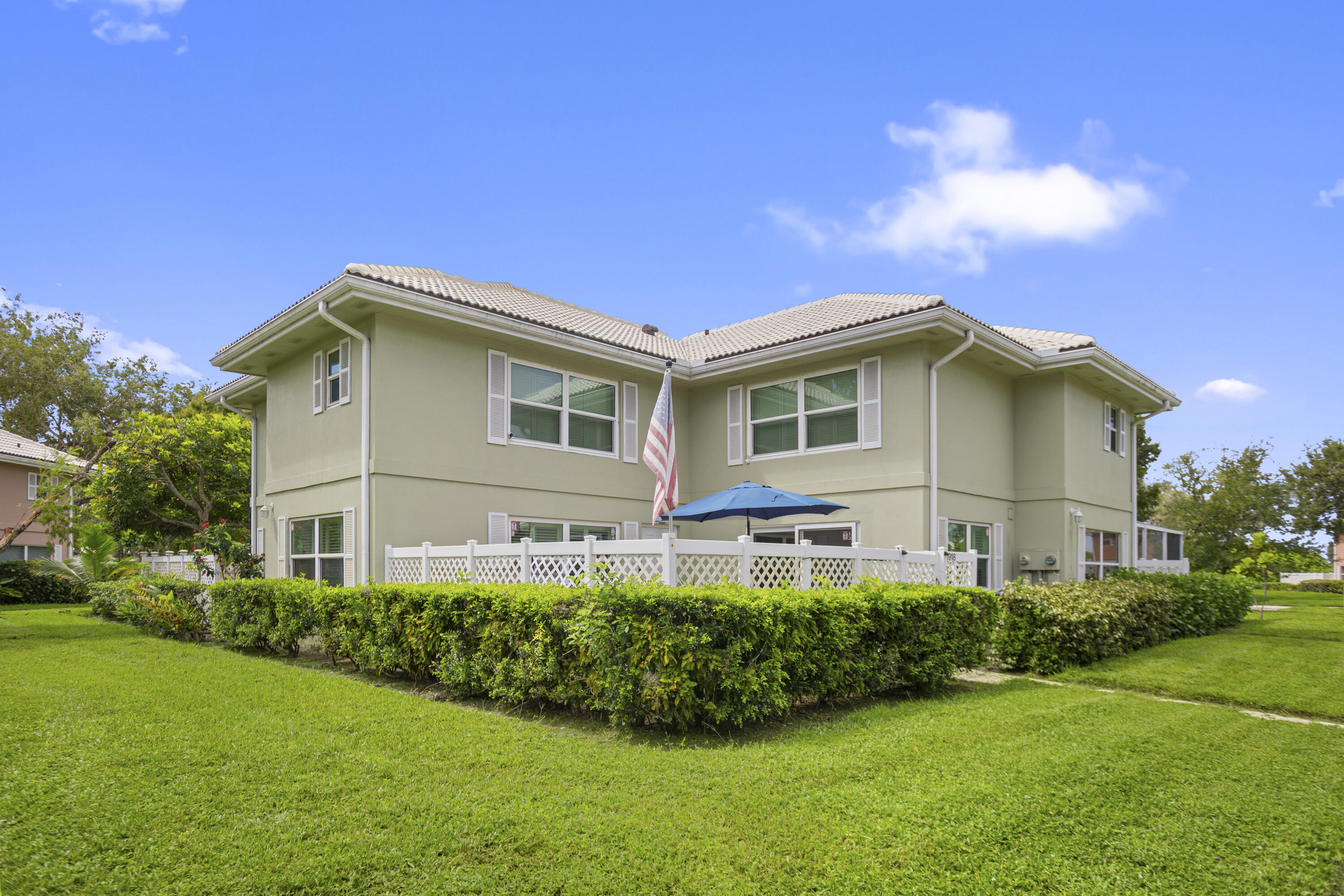 Two-story exterior with a light-colored stucco finish, white window shutters, and a tiled roof
