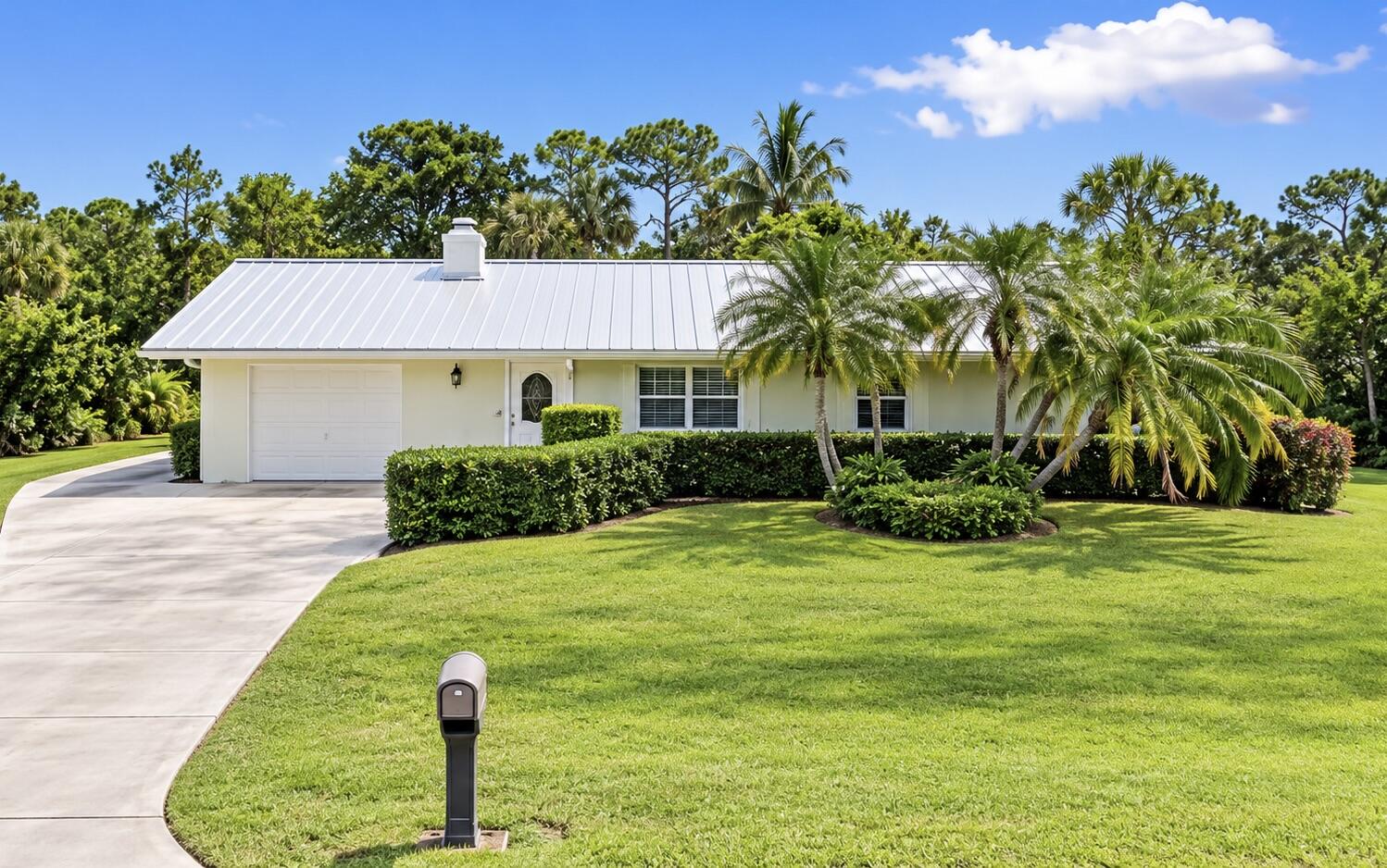 Exterior featuring a metal roof, attached garage with a white door, and a concrete driveway