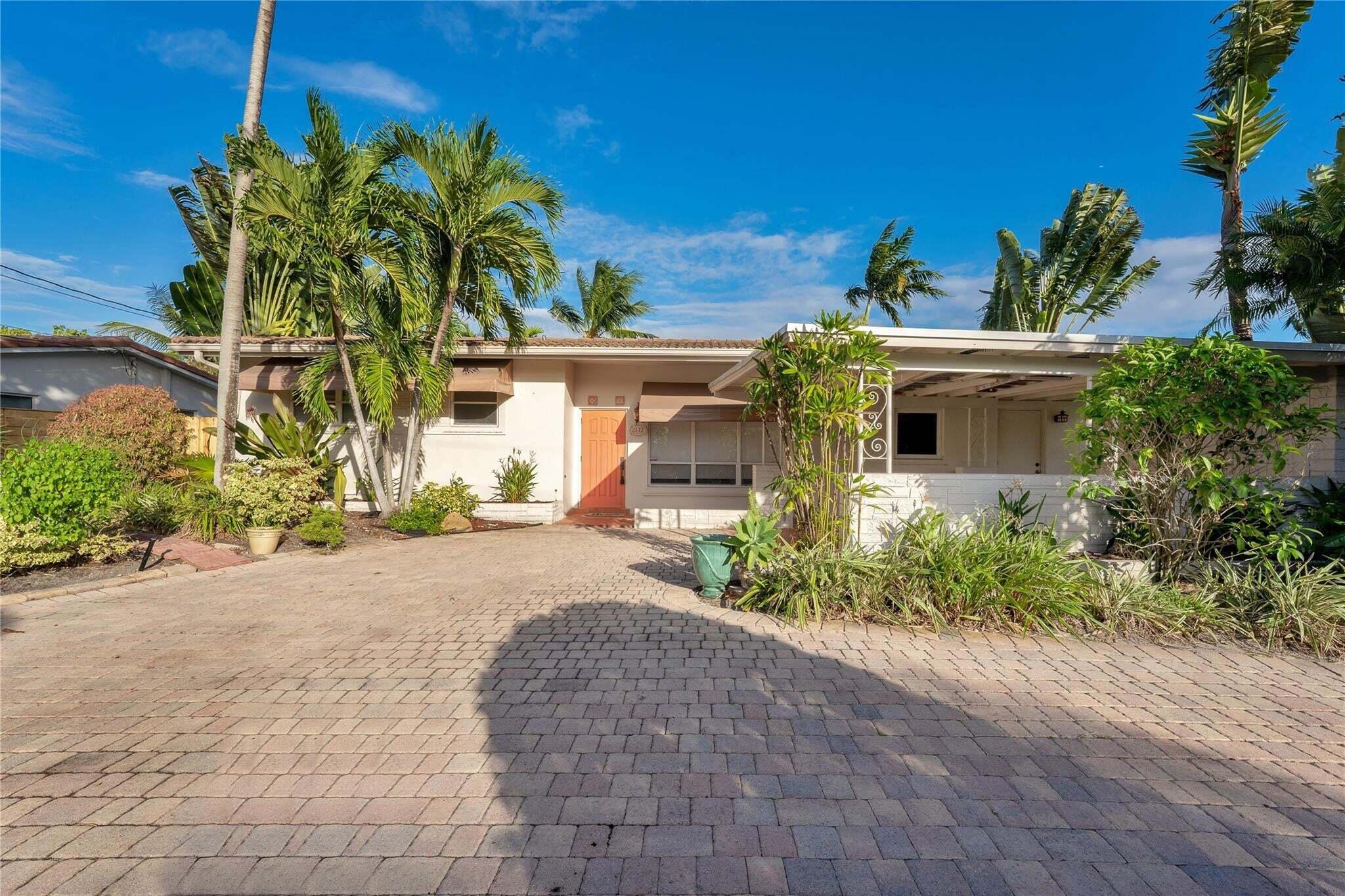 Paved driveway, mature palm trees, exterior awnings, and a covered patio