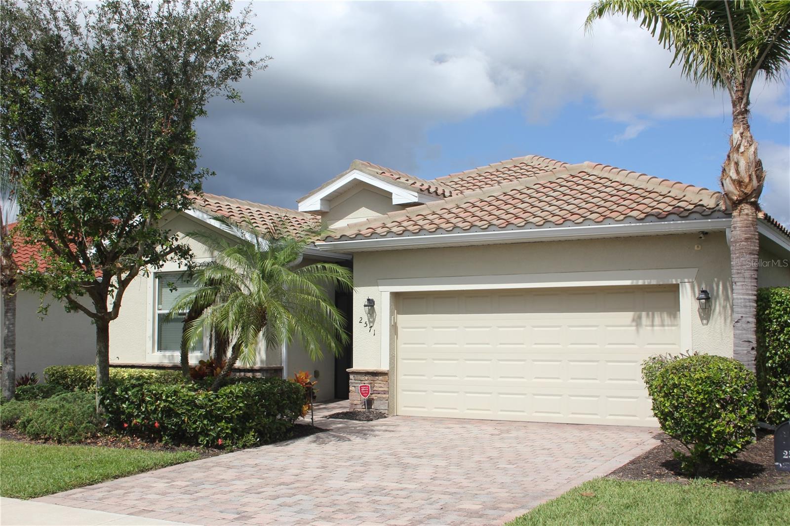 Contemporary Spanish-style home featuring stucco siding, decorative driveway, a tile roof, and an attached garage