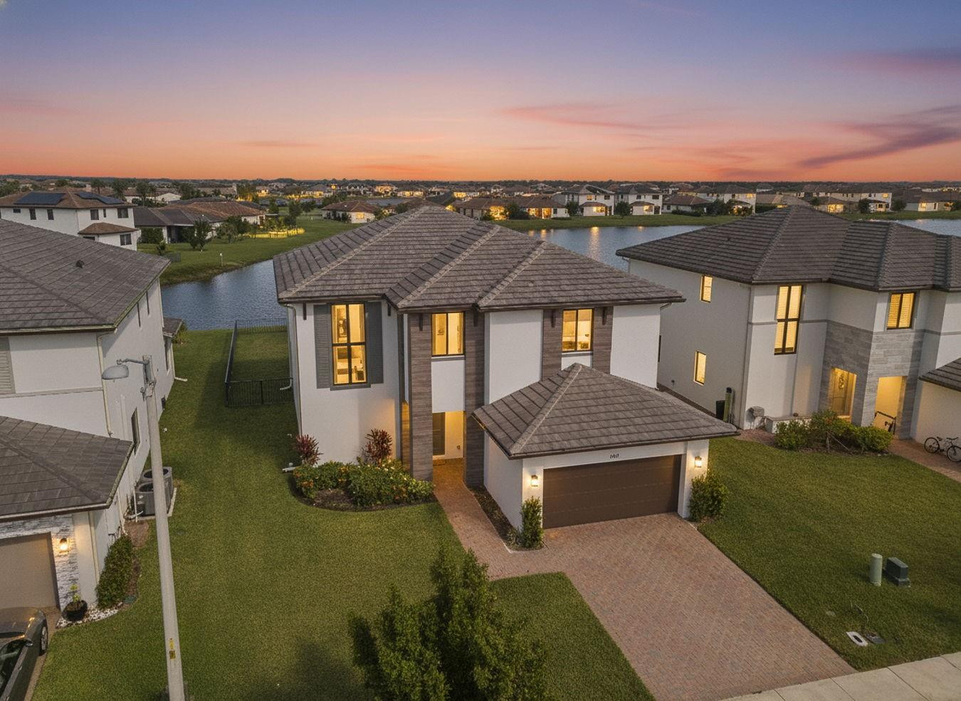View of front of home featuring a tile roof, stucco siding, a yard, and decorative driveway