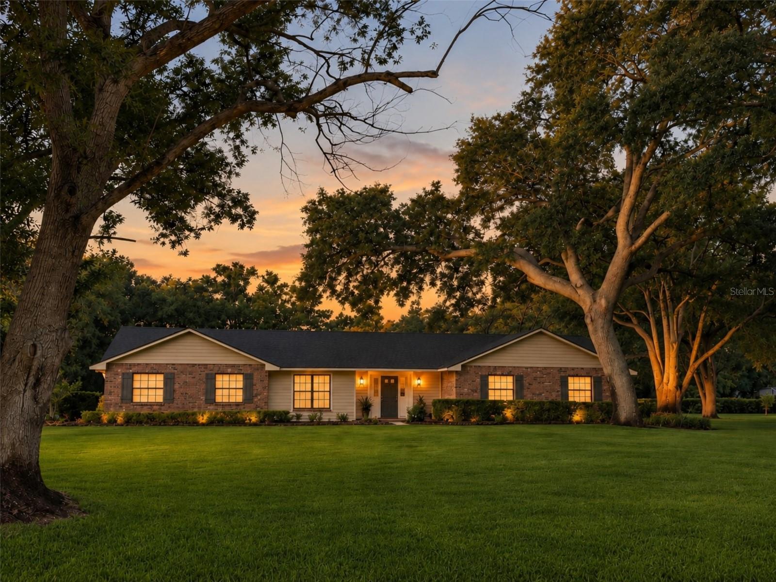 Twilight view of this beautiful pool home on over an acre of land with  mature trees.