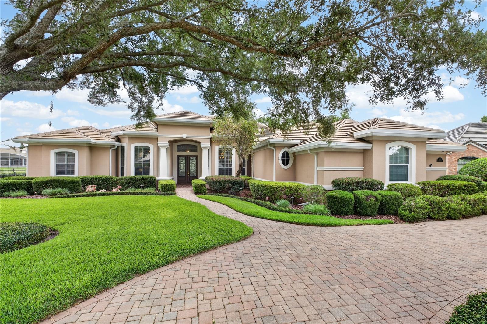 This elegant Mediterranean-inspired residence makes a striking first impression with its sweeping paver driveway, manicured landscaping, and stately architectural details.