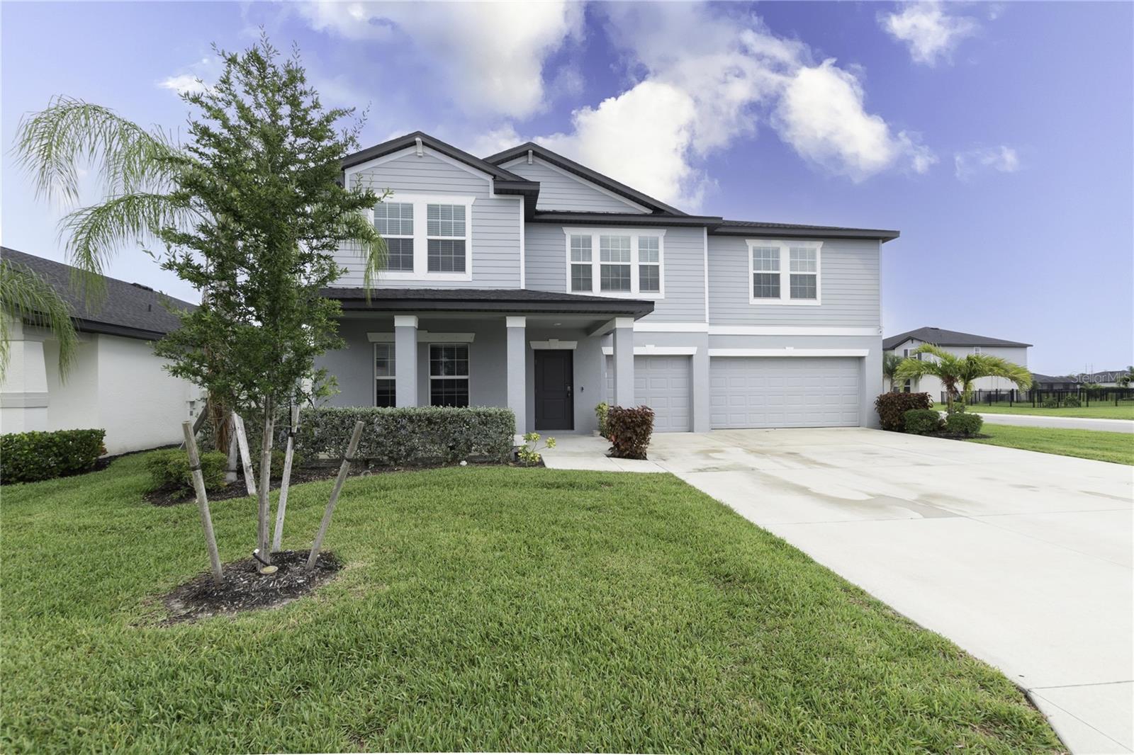 Front elevation of 17177 Monte Isola Way in Crane Landing featuring a three-car garage, covered front porch, and modern 2023 construction in North Fort Myers, FL.
